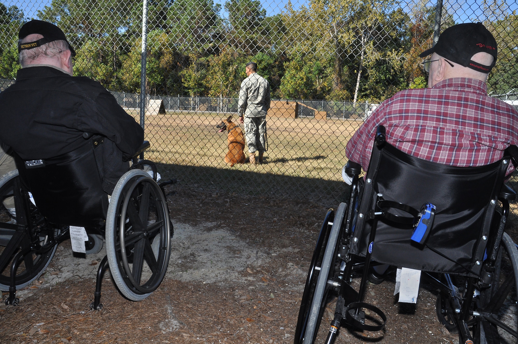 Veterans and community living center residents Leonard Whitaker and Richard Cammer from Ralph H. Johnson VA Medical Center eagerly await a demonstration by a military working dog and his handler Staff Sgt. Fazel Munshi.  The Veterans toured the Joint Base Charleston Nov. 15 as part of the 315th Airlift Wing’s community relations program. (U.S. Air Force Photo/Michael Dukes)
