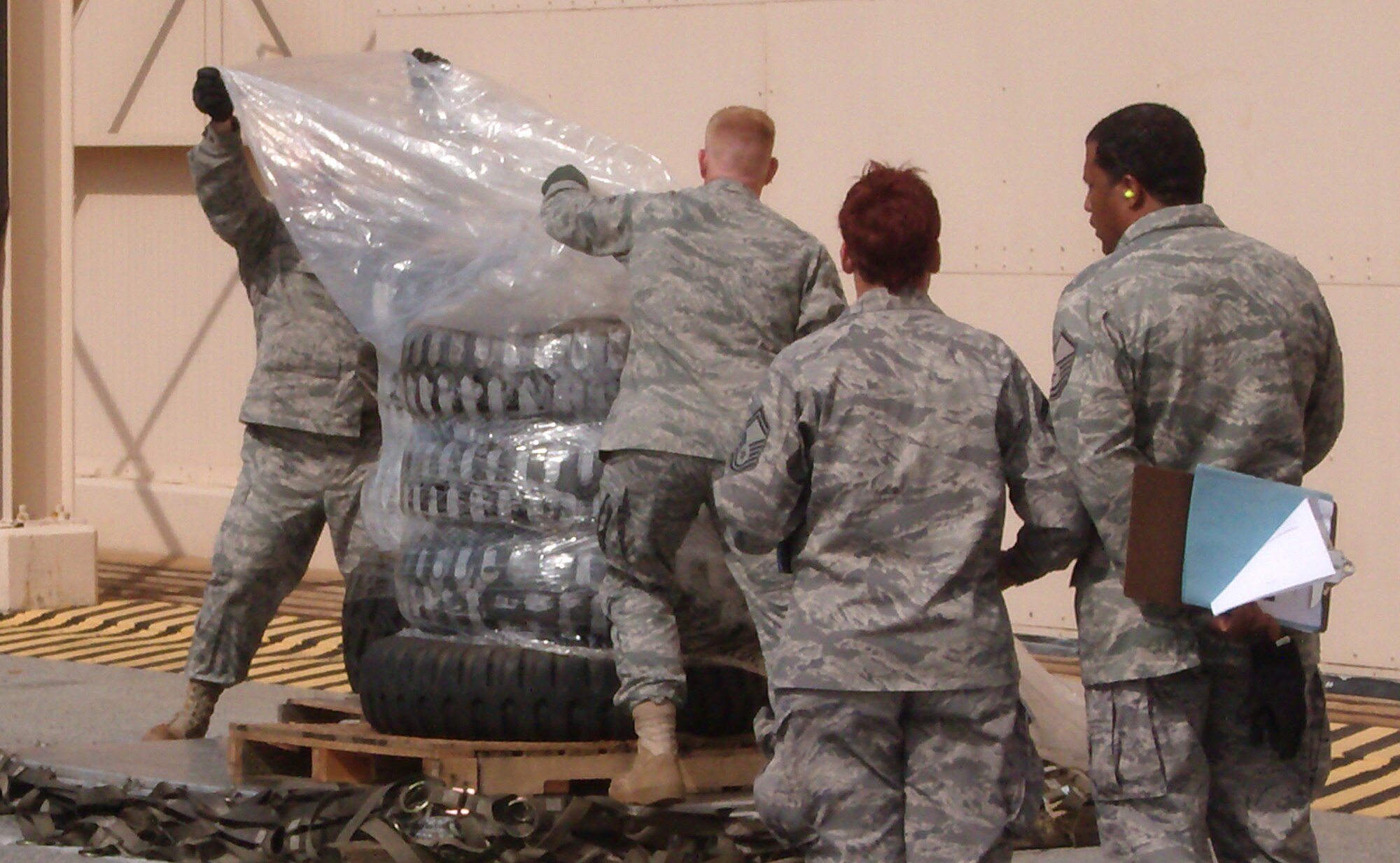 Air Force Reserve Command evaluators watch as Tech. Sgt. Jeremy Jamison (background) and Airman 1st Class Chris Meyer wrap cargo in a protective plastic sheet during a 10K forklift pallet build up competition Oct. 28 at Dobbins Air Reserve Base, Ga. Sergeant Jamison and Airman Meyer joined other 39th Aerial Port Squadron members Oct. 25-29 to compete in the inaugural Air Force Reserve Command Port Dawg Challenge. The event brought together 23 aerial port squadrons in a number of friendly competitions, testing Reservists' speed and accuracy in a variety of aerial port challenges common to the career field. The 39th APS took first place in the timed forklift driving course, while the overall Port Dawg Challenge winners were the 27th APS from Minneapolis-St. Paul Air Reserve Station, Minn. The 39th APS is a subordinate organization to the Colorado-based 302nd Airlift Wing. (U.S. Air Force photo/Lt. Col. Michael Burns)