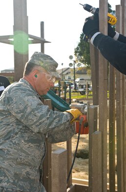Col. Randal Bright, 512th Airlift Wing commander, helps construct the framing of a new playground being built next to the base swimming pool at Dover AFB, De., Nov. 8, 2010. Wing leadership directed a portion of funds obtained from winning the 2010 Air Mobility Command's Commander-in-Chief's Award for Installation Excellence for the park’s construction.  The playground, designed by Leathers and Associates, features swings, slides and other play areas contained inside a huge shell resembling a large cargo military aircraft. It could be a C-17 or a C-5, depending on how you look at it. The park is being built by more than 900 base volunteers. (U.S. Air Force Photo/Roland Balik)