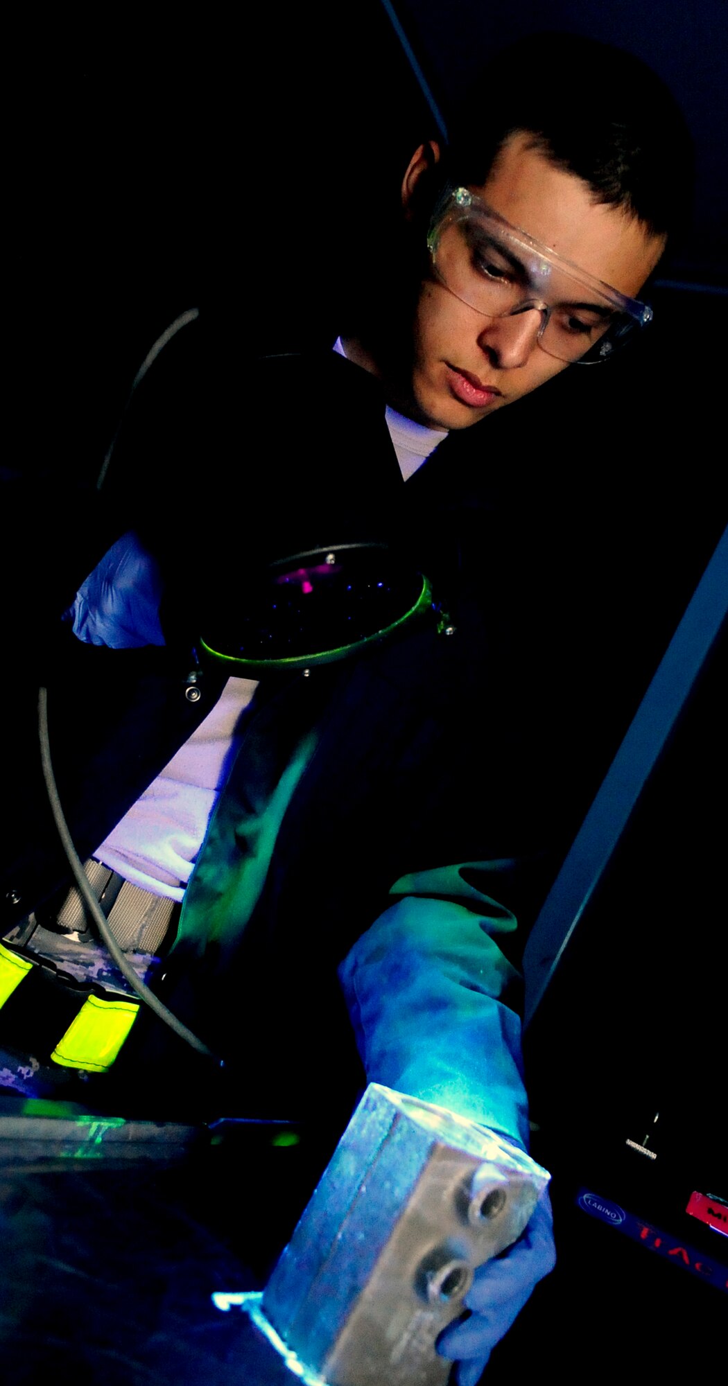 RAF MILDENHALL, England -- Airman 1st Class Christopher Bovill, 100th Maintenance Squadron non destructive journeyman, shines a black light onto a KC-135 nose landing gear hydraulic sub-assembly during a fluorescent liquid penetrant inspection Nov. 16, 2010. The black light is used to determine where the cracks in the landing gear are by making the florescent dye penetrant that resides in the cracks glow. (U.S. Air Force photo/Senior Airman Ethan Morgan)