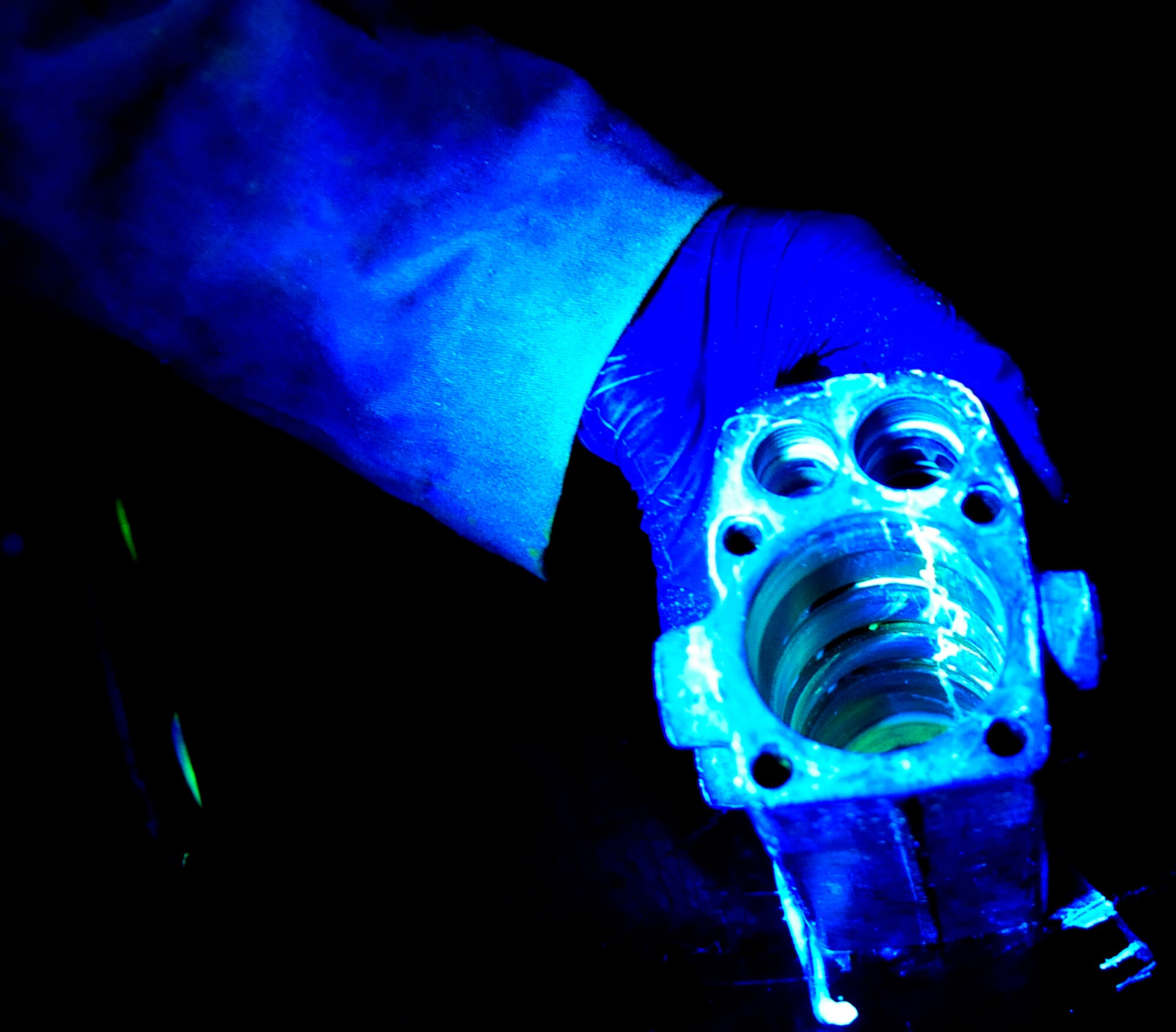 RAF MILDENHALL, England -- A KC-135 nose landing gear hydraulic sub-assembly is examined under a black light during a fluorescent liquid penetrant inspection Nov. 16, 2010. The black light makes any penetrant that is present in any cracks that may be in the landing gear glow showing the exact location of the damage. (U.S. Air Force photo/Senior Airman Ethan Morgan)
