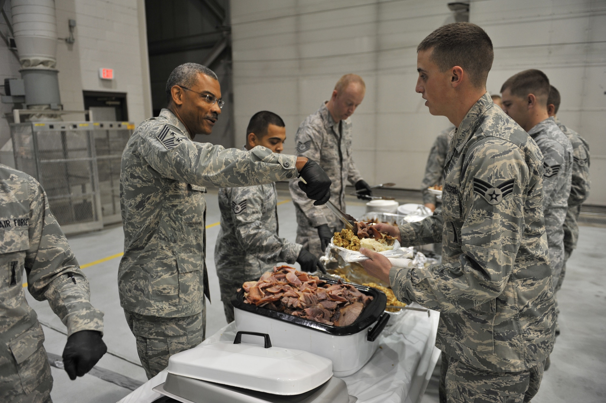 Chief Master Sgt. Jack Johnson helps Staff Sgt. Lawrence Blanco and Tech. Sgt. Jace Pape serve a Thanksgiving-styled lunch to maintenance troops and their families at the 341st Maintenance Group’s “turkey feed” Nov. 10 in the 3-Bay Hangar.    (U.S. Air Force photo/ John Turner)