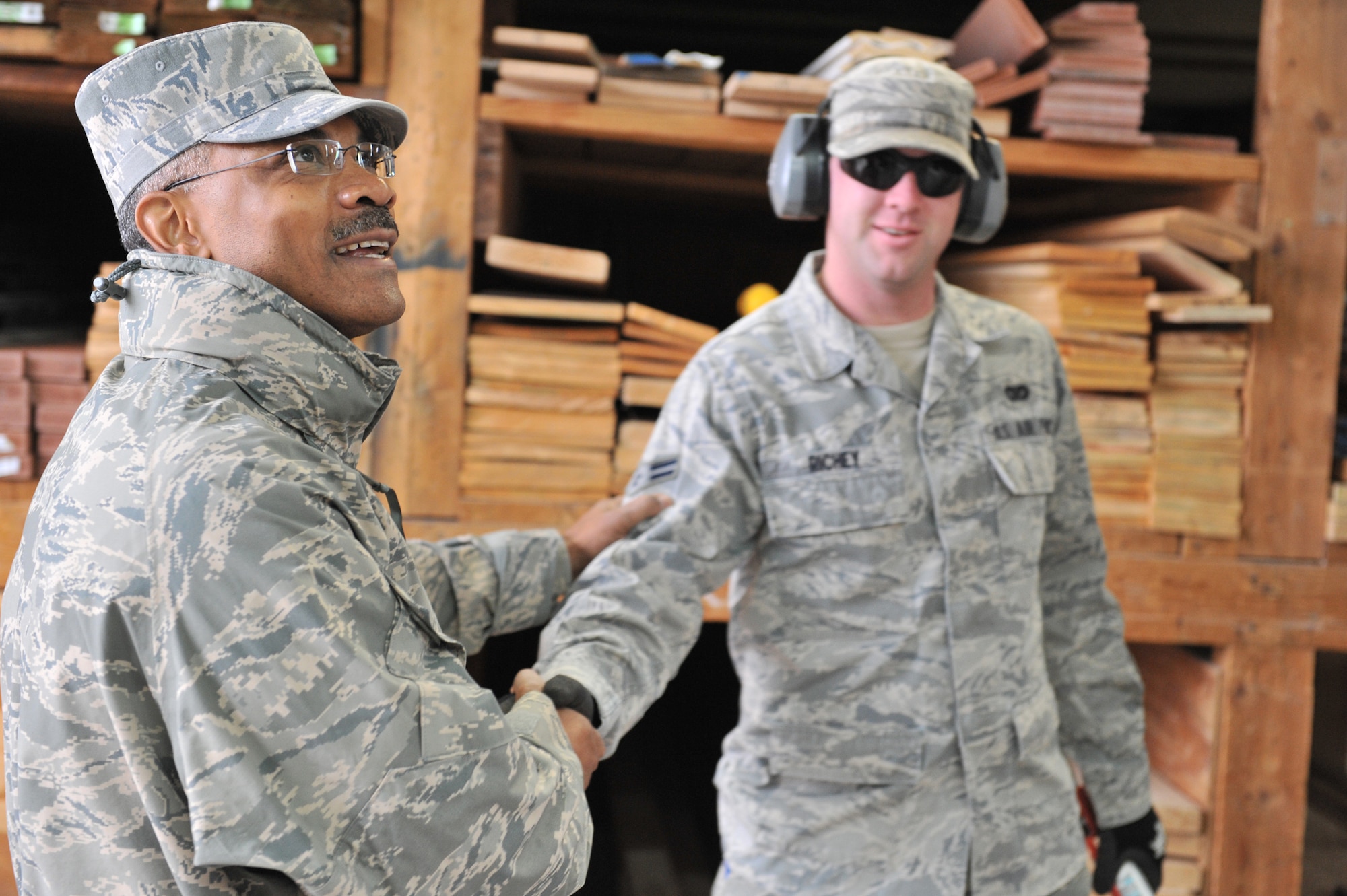 Chief Master Sgt. Jack Johnson shakes the hand of Airman 1st Class Jacob Richey, a 341st Civil Engineer Squadron structures apprentice, while admiring a shelter that the structures shop is constructing.  (U.S. Air Force photo/ John Turner)