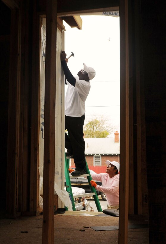 LANGLEY AIR FORCE BASE, Va. -- Tech. Sgt. Elroy Williams, Headquarters Air Combat Command Ceremony NCOIC, works atop a ladder steadied by his wife, Nicole, during a Habitat for Humanity project Oct. 15. Sergeant Williams and his family received the Armed Forces YMCA of Hampton Roads’ Five-Star Air Force Military Family of the Year award for their collective contribution of community service, including volunteer work, organizing a foundation for military spouses and families to escape domestic violence, and serving on local schools’ parent-teacher associations. (Photo courtesy/Tech. Sgt. Elroy Williams)(RELEASED)