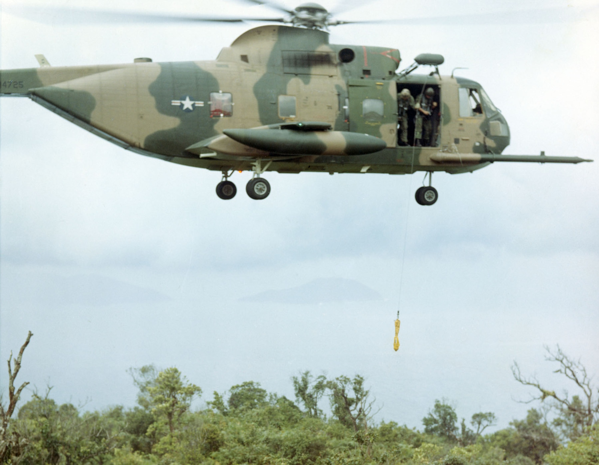 Equipped with a powerful external winch, the Jolly Green Giants could extract a downed pilot without landing. Here, an aircrew practices lowering a jungle penetrator. (U.S. Air Force photo)