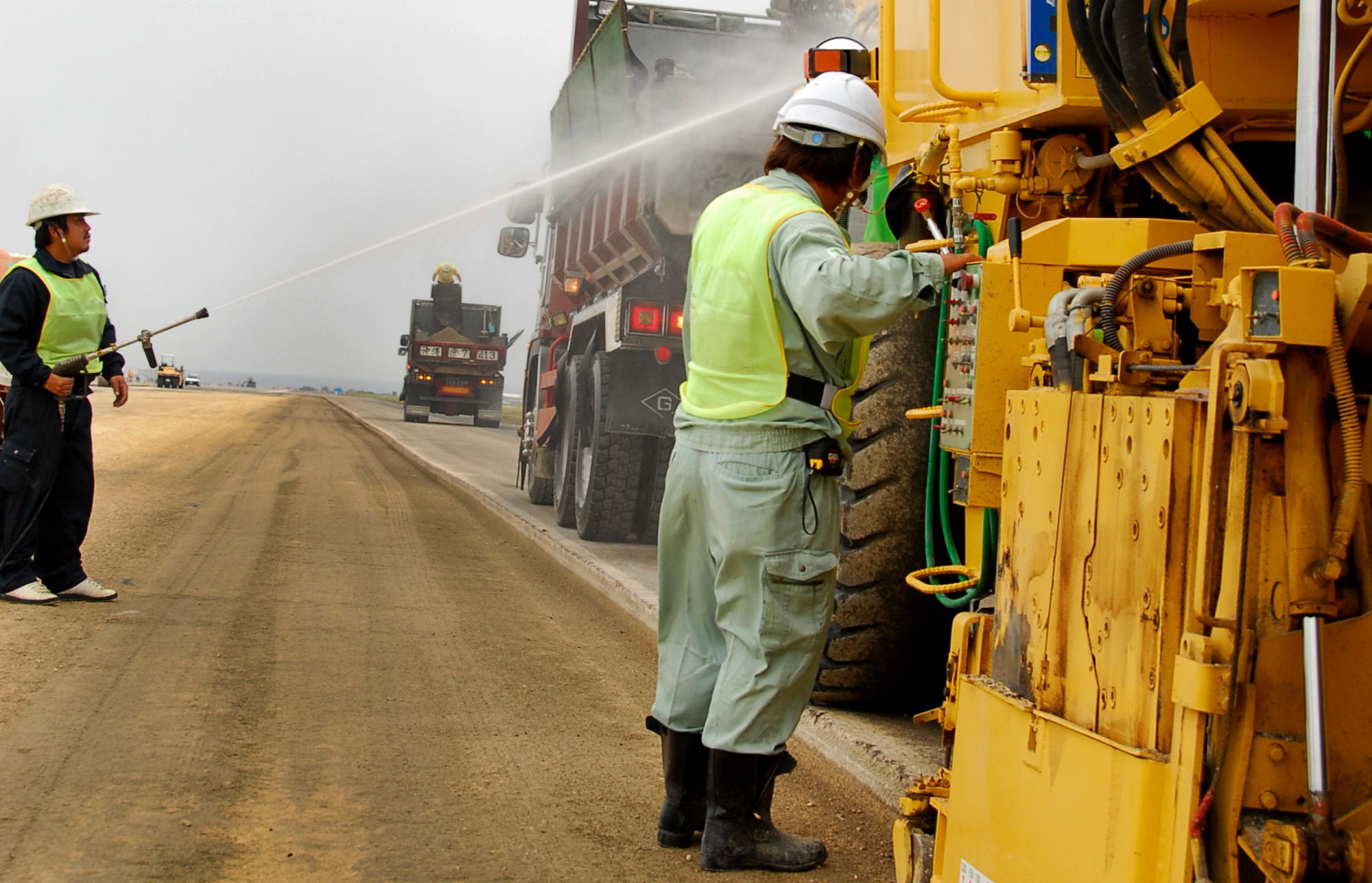 A contractor working on Kadena's runway reconstruction saturates asphalt as it's transferred to the back of a dump truck to keep down dust. The 18-month reconstruction project began Oct. 4. (U.S. Air Force photo/ Airman 1st Class Maeson L. Elleman)
