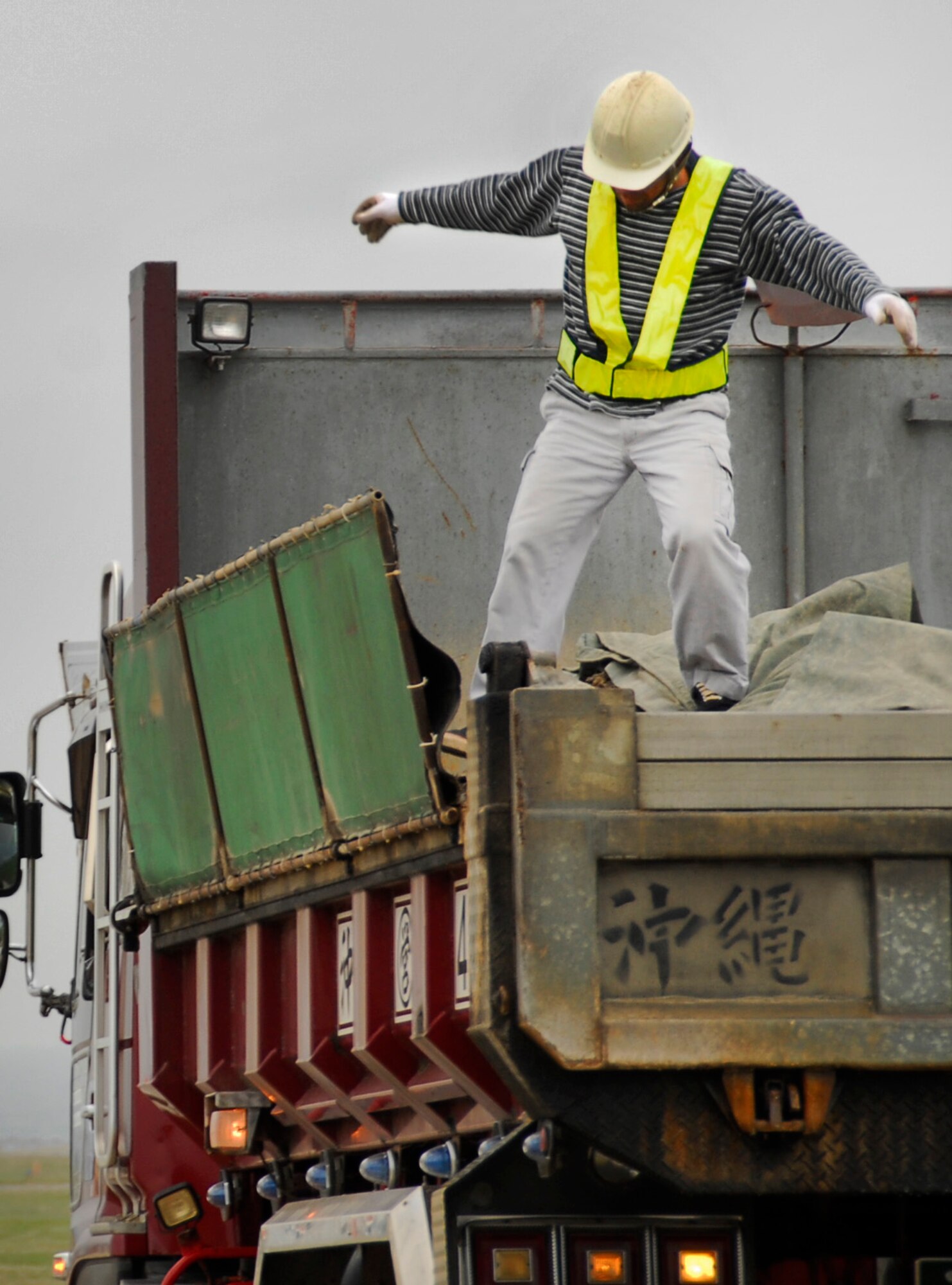 A contractor working on Kadena's runway reconstruction covers the milled-up asphalt in the back of a dump truck to keep down debris during transfer. The old asphalt is transferred to a recycling facility to be used in future Okinawan road projects. (U.S. Air Force photo/ Airman 1st Class Maeson L. Elleman)