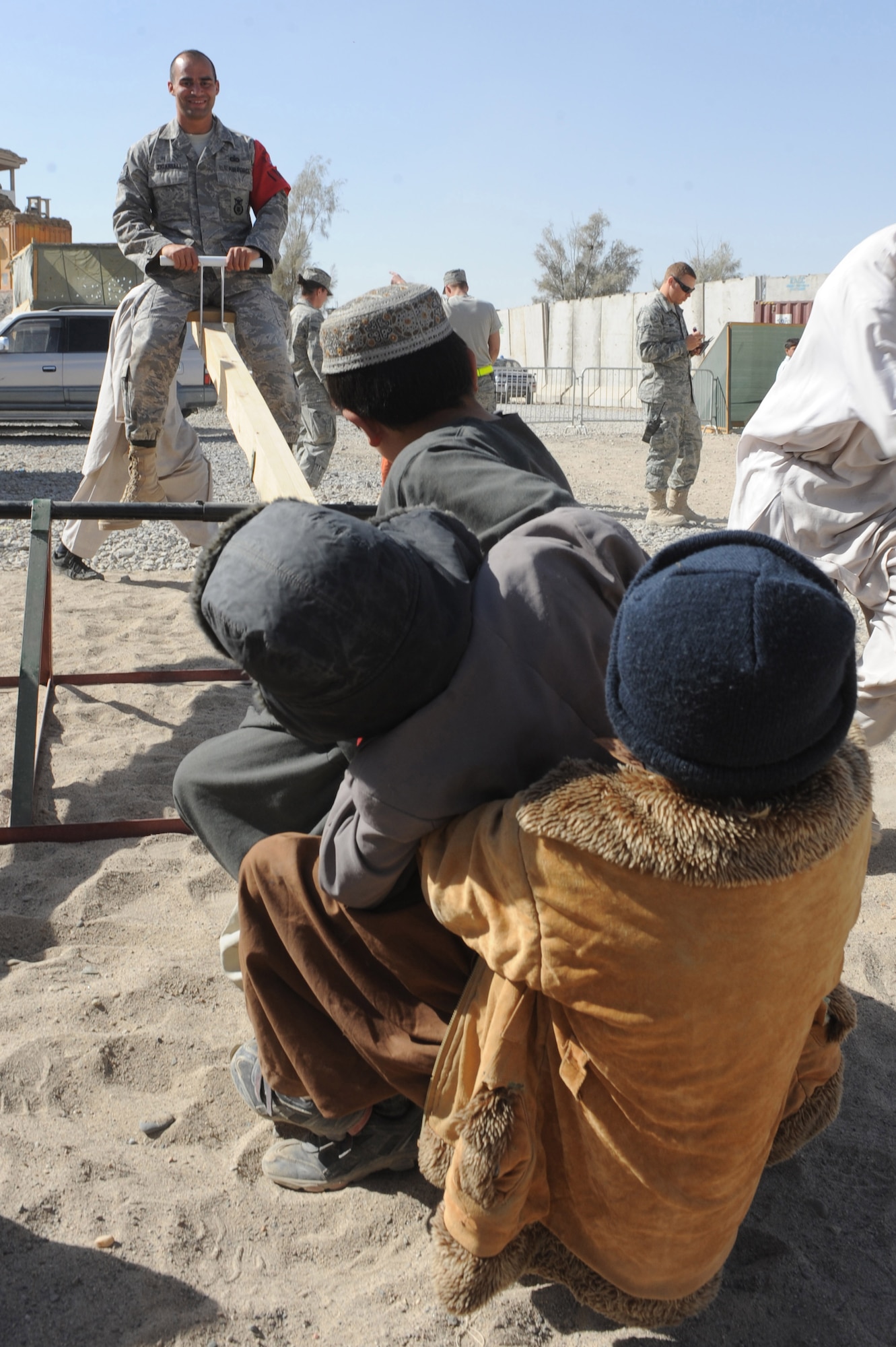 Tech. Sgt. Michael Zigarelli plays with a group of Afghan children on a seesaw Nov. 13, 2010, at Kandahar Airfield, Afghanistan. Sergeant Zigarelli, from Belleville, N.J., is a patrolman with the International Security Assistance Force Military Police. (U.S. Air Force photo by Tech. Sgt. Chad Chisholm/Released) 