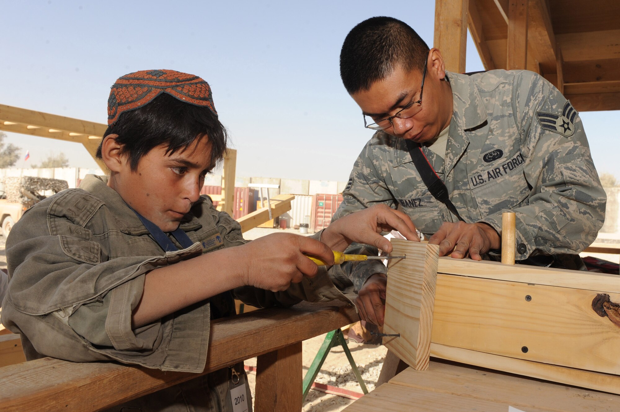Senior Airman Ismael Ibanez constructs a birdhouse with an Afghan child at the bazaar school Nov. 13, 2010, at Kandahar Airfield, Afghanistan. Airman Ibanez, from Chicago, is a client system journeyman assigned to the 451st Expeditionary Communications Squadron. (U.S. Air Force photo by Tech. Sgt. Chad Chisholm/Released) 