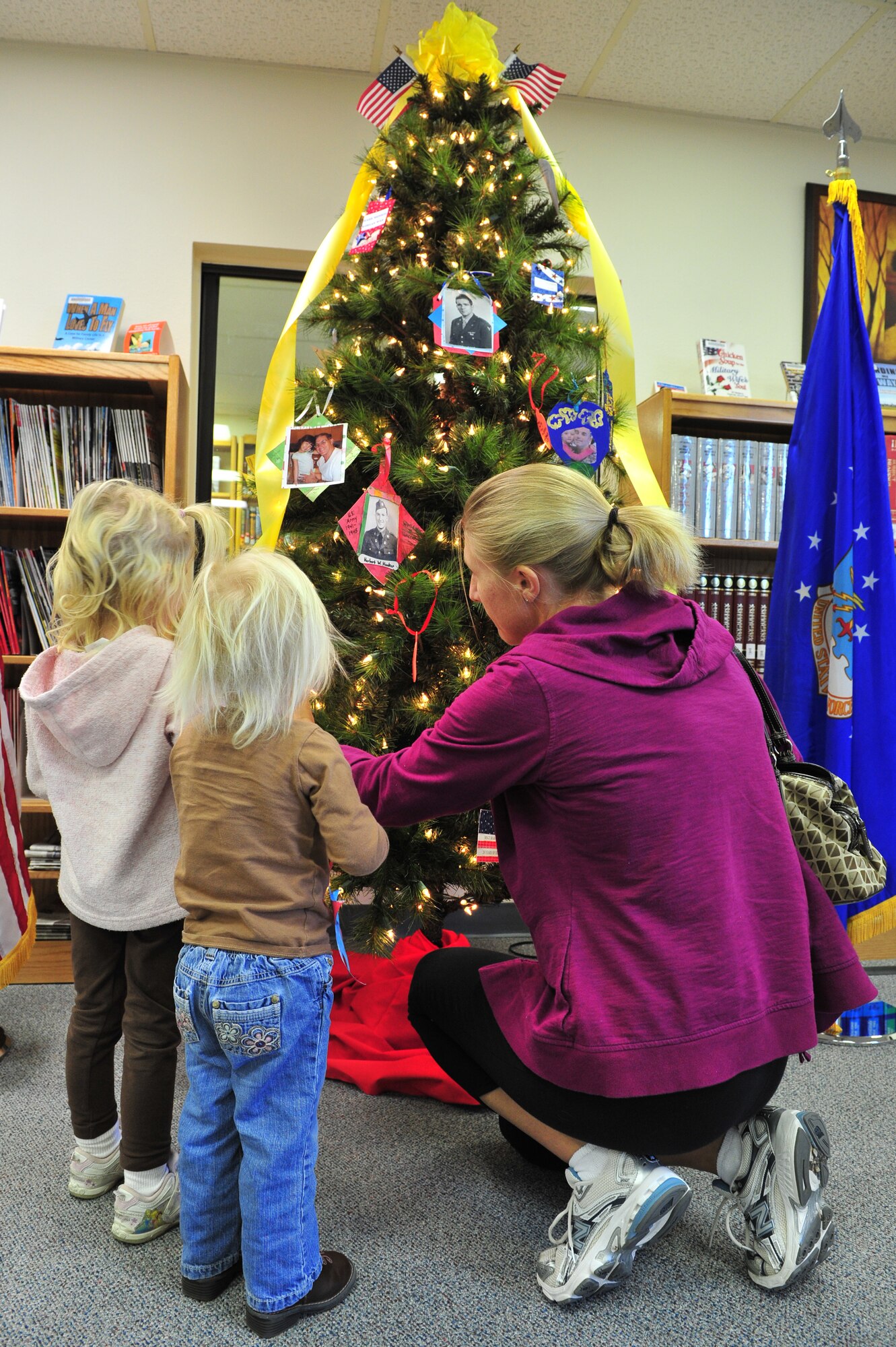 A family places ornaments during a Heroes' Tree Dedication ceremony at the base library, Nov. 14, 2010. Our Heroes' Tree is a community outreach program co-founded in 2005 by Stephanie Pickup, author of The Soldiers' Tree, and Marlene Lee, author of The Hero in My Pocket. This program promotes awareness of the service and sacrifice of U.S. service members and their families. (U.S. Air Force photo by Tech Sgt. Josef Cole)(RELEASED) 