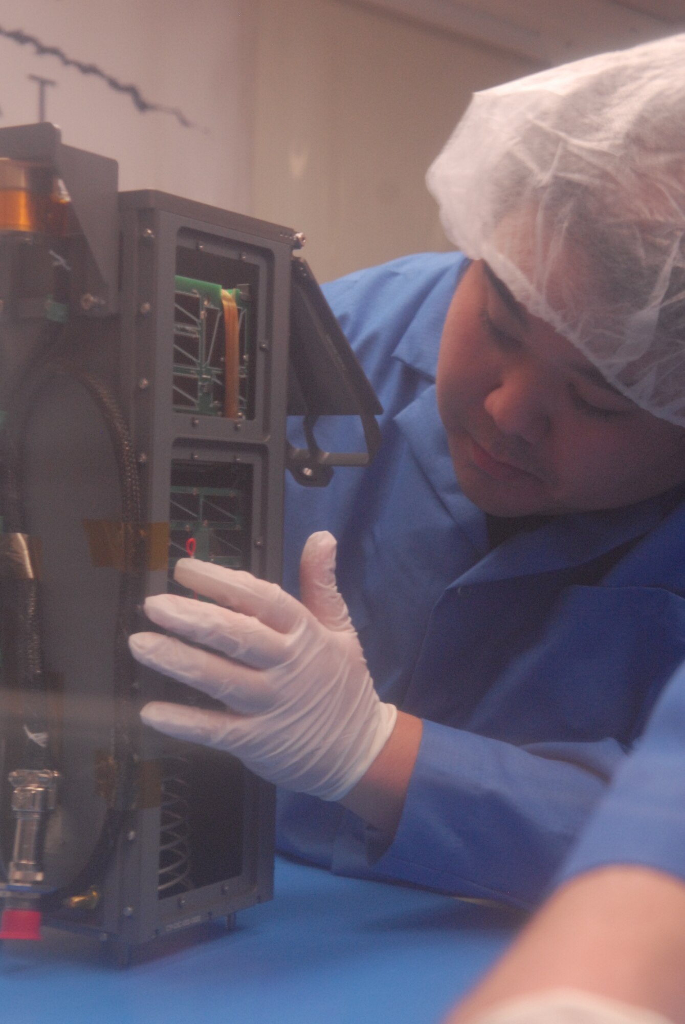 SAN LUIS OBISPO, Calif. – Roland Coelho, an aerospace engineering student at California Polytechnic State University, inspects the integration alignment of mini research satellites, or CubeSats, into a Poly Picosatellite Orbital Deployer, or PPOD, container. The PPOD and CubeSat Project were developed by California Polytechnic State University and Stanford University’s Space Systems Development Lab for use on NASA’s Educational Launch of Nanosatellite, or ELaNa missions. Each CubeSat measures about four inches cubed; about the same volume as a quart. The CubeSats weigh about 2.2 pounds, must conform to standard aerospace materials and must operate without propulsion. (U.S. Air Force photo/Jerry E. Clemens, Jr.)