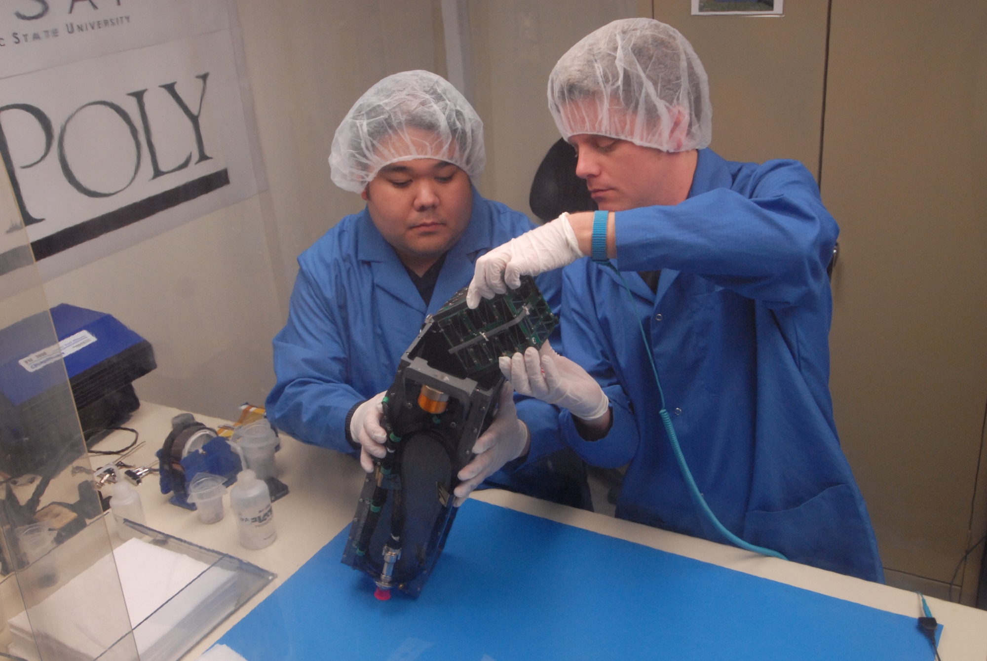 SAN LUIS OBISPO, Calif. – Roland Coelho and Ryan Nugent, aerospace engineering students at California Polytechnic State University, integrate mini research satellites, or CubeSats. into a Poly Picosatellite Orbital Deployer, or PPOD, container. The PPOD and CubeSat Project were developed by California Polytechnic State University and Stanford University’s Space Systems Development Lab for use on NASA’s Educational Launch of Nanosatellite, or ELaNa missions. Each CubeSat measures about four inches cubed; about the same volume as a quart. The CubeSats weigh about 2.2 pounds, must conform to standard aerospace materials and must operate without propulsion.(U.S. Air Force photo/Jerry E. Clemens, Jr.)