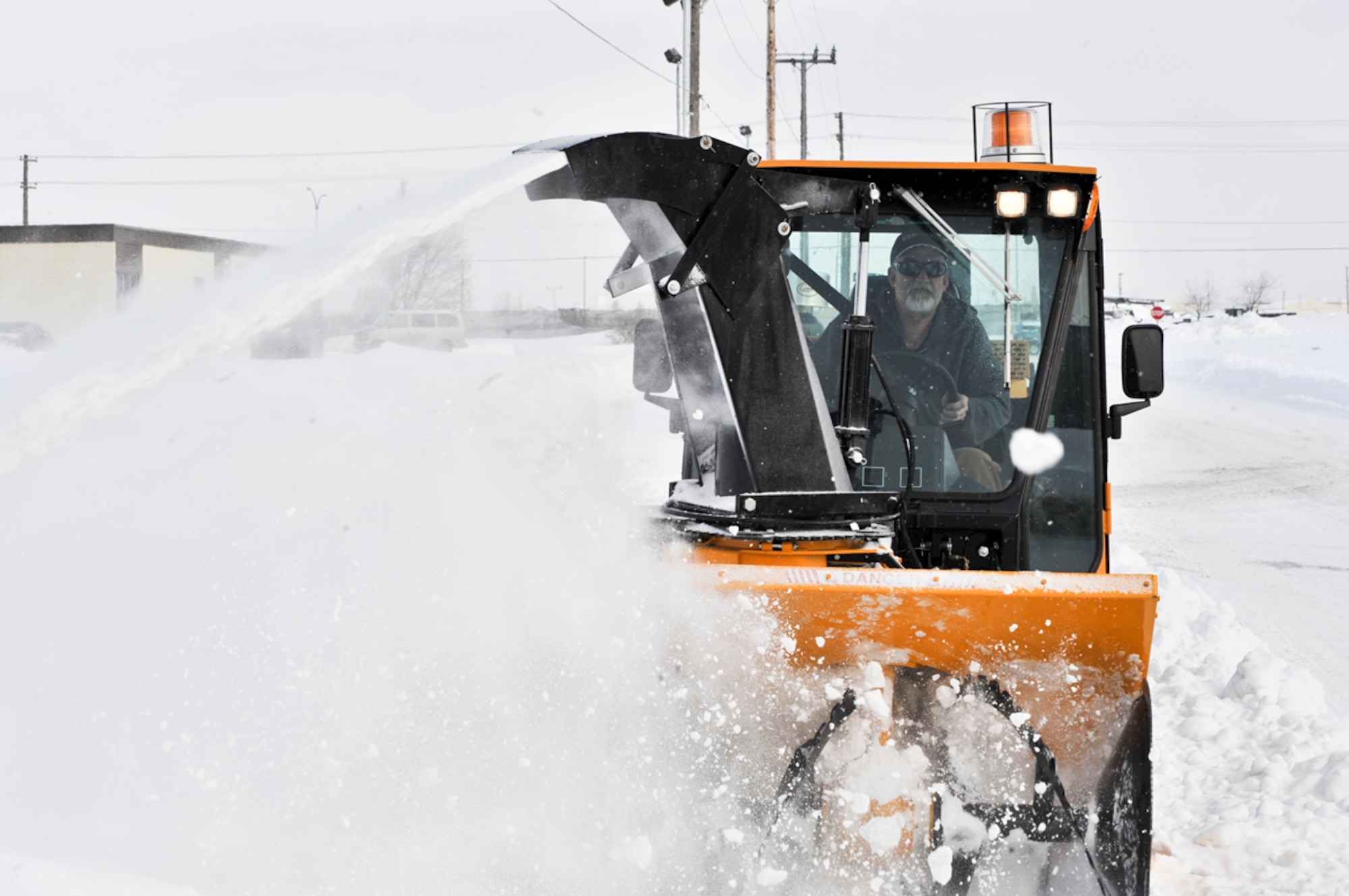An operator drives a snow removal vehicle, blowing snow off a Joint Base Elmendorf-Richardson street. (U.S. Air Force photo/A1C Jack Sanders)