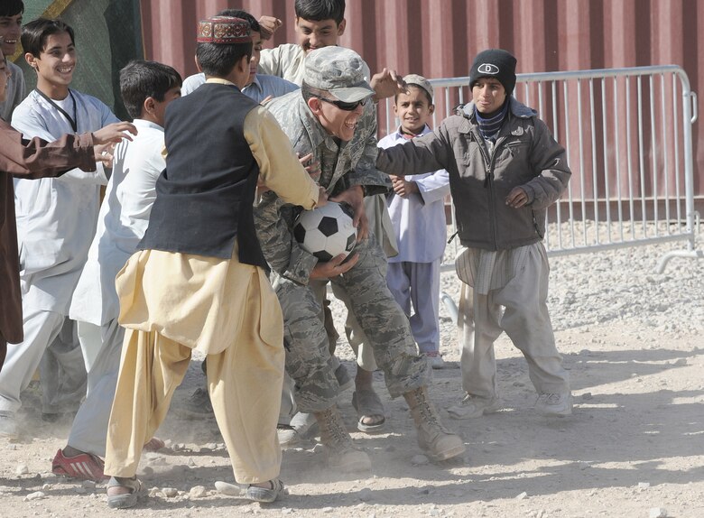 Senior Airman Jonathan Armstrong gets stopped with the soccer ball by local Afghan children while playing a game at the bazaar school Nov. 13, 2010, at Kandahar Airfield, Afghanistan. Airman Armstrong is a vehicle operator and dispatcher assigned to the 451st Expeditionary Logistics Readiness Squadron. (U.S. Air Force photo by Tech. Sgt. Chad Chisholm)