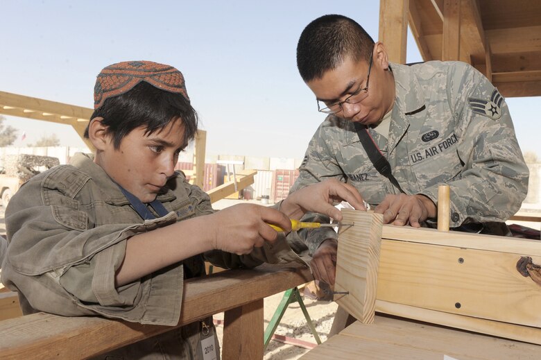 Senior Airman Ismael Ibanez constructs a birdhouse with an Afghan child at the bazaar school Nov. 13, 2010, at Kandahar Airfield, Afghanistan. Airman Ibanez is a client system journeyman assigned to the 451st Expeditionary Communications Squadron. (U.S. Air Force photo/Tech. Sgt. Chad Chisholm)
