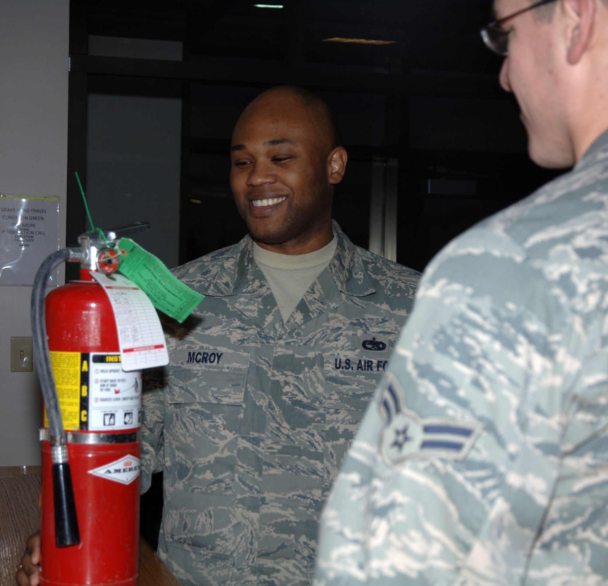 Staff Sgt. Jonathan McRoy, 319th Civil Engineer Squadron, demonstrates how to check a fire extinguisher to his bay orderly Nov. 18. Sergeant McRoy is the Warrior of the Week for Nov. 15 through the 19. (U.S. Air Force photo by Airman 1st Class Rachel Waller)