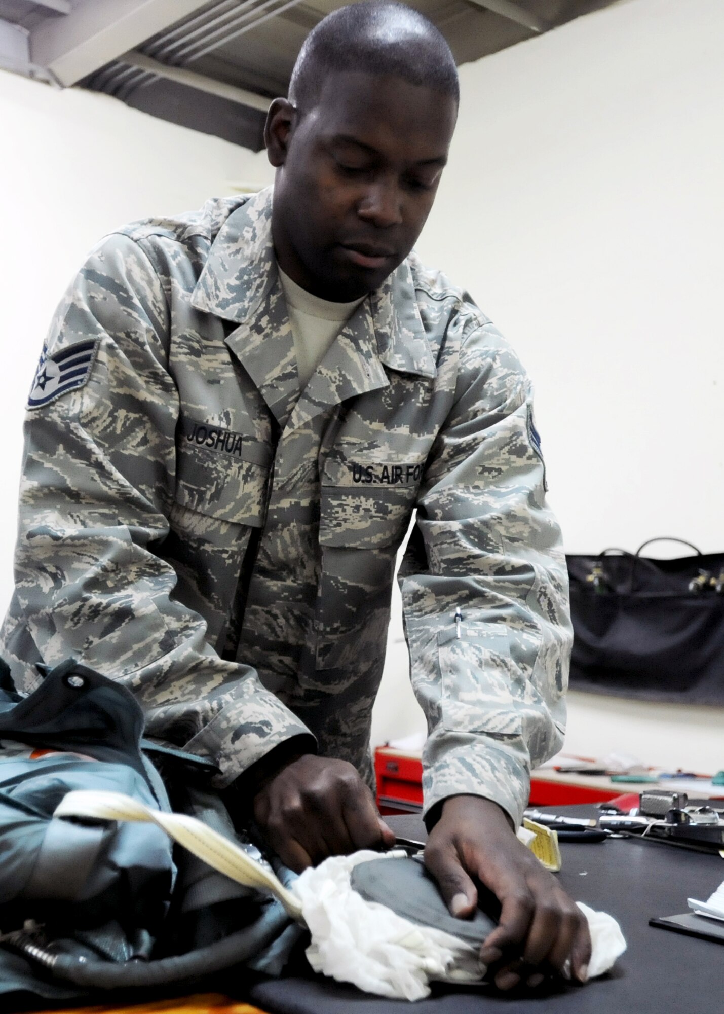 SOUTHWEST ASIA -- Staff Sgt. Venie Joshua, the NCO in charge of the 386th Expeditionary Operations Support Squadron's aircrew flight equipment shop, inspects a parachute Nov. 11, 2010, at an undisclosed air base here. Flight equipment Airmen inspect, service and provide aircrews with a broad range of gear that could save their lives if they encounter an in-flight-emergency while flying airlift sorties across the U.S. Central Command's area of responsibility. (U.S. Air Force photo by Senior Airman Laura Turner)