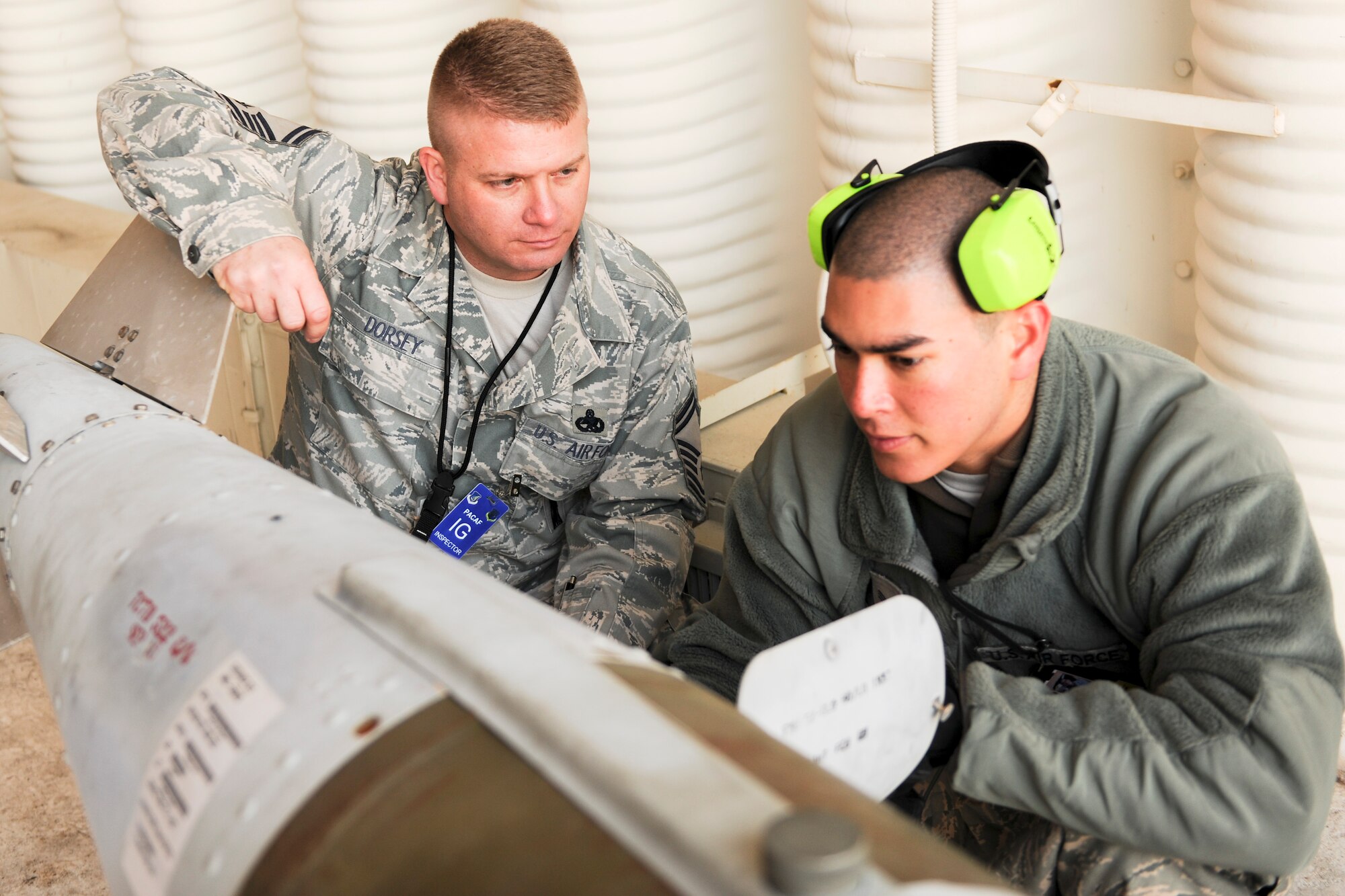 KUNSAN AIR BASE, Republic of Korea -- Senior Master Sgt. Benjamin Dorsey, Pacific Air Force Command Inspector General, listens to an 8th Fighter Wing maintainer as they review the proper procedures of safety checking munitions before loading them onto aircraft.  The wing participated in the Phase 1 operational readiness inspection Beverly Bearcat 10-06 that tested the wing's prepartion and mobilization from peacetime readiness into wartime posture. (U.S. Air Force photo/Staff Sgt. Jonathan Pomeroy)