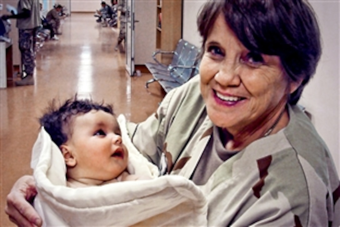 U.S. Navy Petty Officer 1st Class Billie B. Estes holds a newly born Afghan child, Kandahar Airfield, Afghanistan, Nov. 16, 2010. Estes treats patients from coalition forces and local nationals daily. Estes, a U.S. Navy hospital corpsman and intensive care ward leading petty officer, is assigned to NATO Role 3, Multinational Medical Unit. She also has been a licensed nurse practitioner for 26 years.