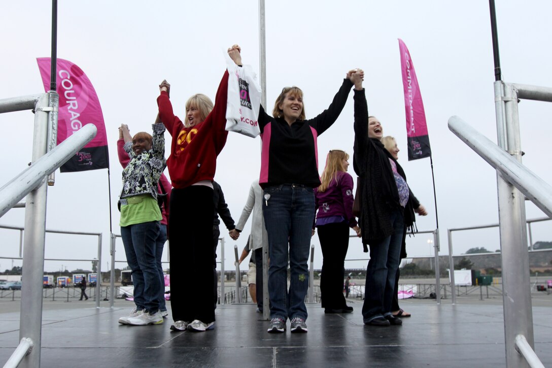 Theresa Hunt (far left), a retired Marine spouse, is among eight breast cancer survivors who raise their hands in victory of defeating the disease. The eight ladies were chosen to carry eight flags Nov. 19-21, with one of the following words on each flag: courage, commitment, love, hope, patience, optimism, belief, and healing, during the “Susan G. Komen 3-Day for the Cure” walk. Hunt was also recognized for raising more than $78,000 for breast cancer research.