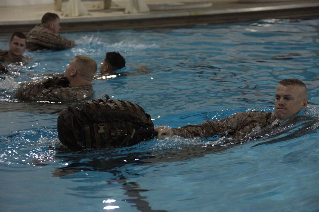 Gunnery Sgt. Michael Eason, an administration chief with Officer Candidate School, Marine Corps Base Quantico, Va., with assault pack in tow, swims to the opposite side of the pool during a demonstration for the new Marine Combat Water Survival Training, Nov. 19, 2010. One portion of the demo had the Marines use their assault pack as a floatation device.