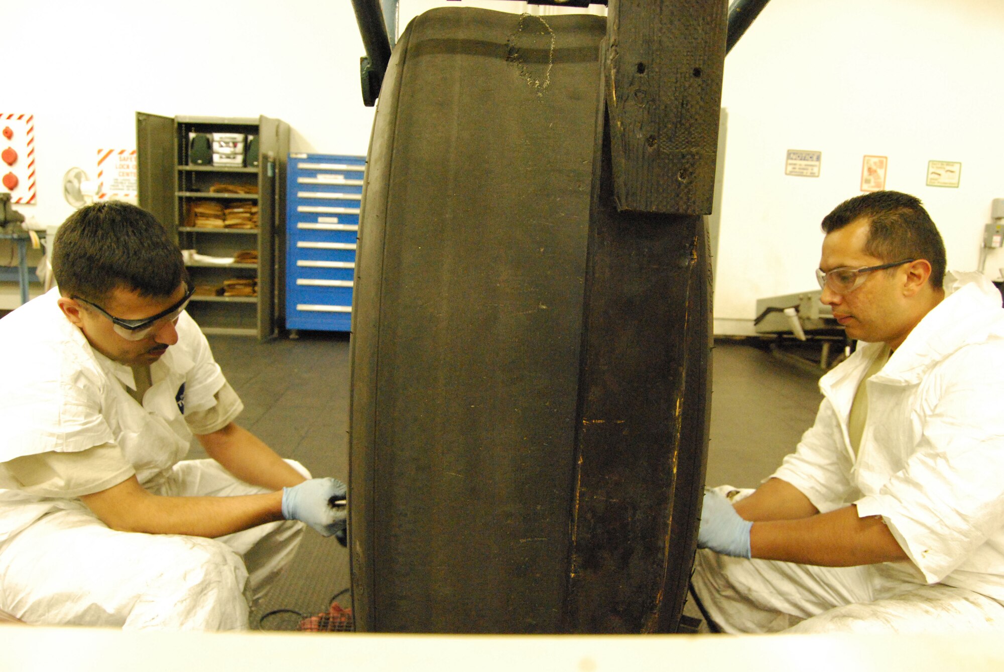 Staff Sgt. George Meza, left, and Staff Sgt. Charles Morales Jr. are both maintainers with the 433rd Wheel and Tire Shop. They are working on the main landing gear wheel and tire assembly from an Alamo Wing C-5 Galaxy. (U.S. Air Force Photo/Master Sgt. Collen McGee)
