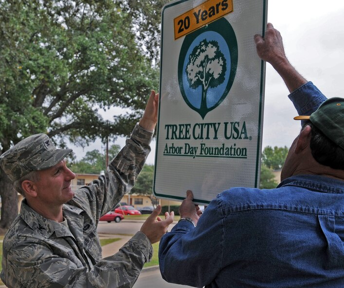 Col. Tim Fay, 2nd Bomb Wing commander, helps Everett Lejeune from the 2nd Civil Engineer Squadron replace the old Tree City USA sign at Barksdale Air Force Base, La., Nov. 19. The Tree City USA program, sponsored by the Arbor Day Foundation provides direction, technical assistance, public attention, and national recognition for urban and community forestry programs. Barksdale has been recognized by Tree City USA for 20 consecutive years, every 10 years the sign is updated. (U.S. Air Force photo/Senior Airman Brittany Y. Bateman)(RELEASED) 
