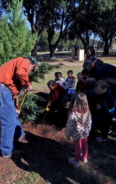 Children from Barksdale Child Development Center assist Mr. Everett Lejeune, Barksdale's Natural Resources urban forester, plant a Leyland Cypress tree in front of Chapel 1 on Barksdale Air Force Base, La., Nov. 17. The tree was planted in observance of the Barksdale Arbor Day Celebration. Arbor Day is an observance that encourages tree planting, care and preservation. (U.S. Air Force photo/Senior Airman La'Shanette V. Garrett)(RELEASED)
