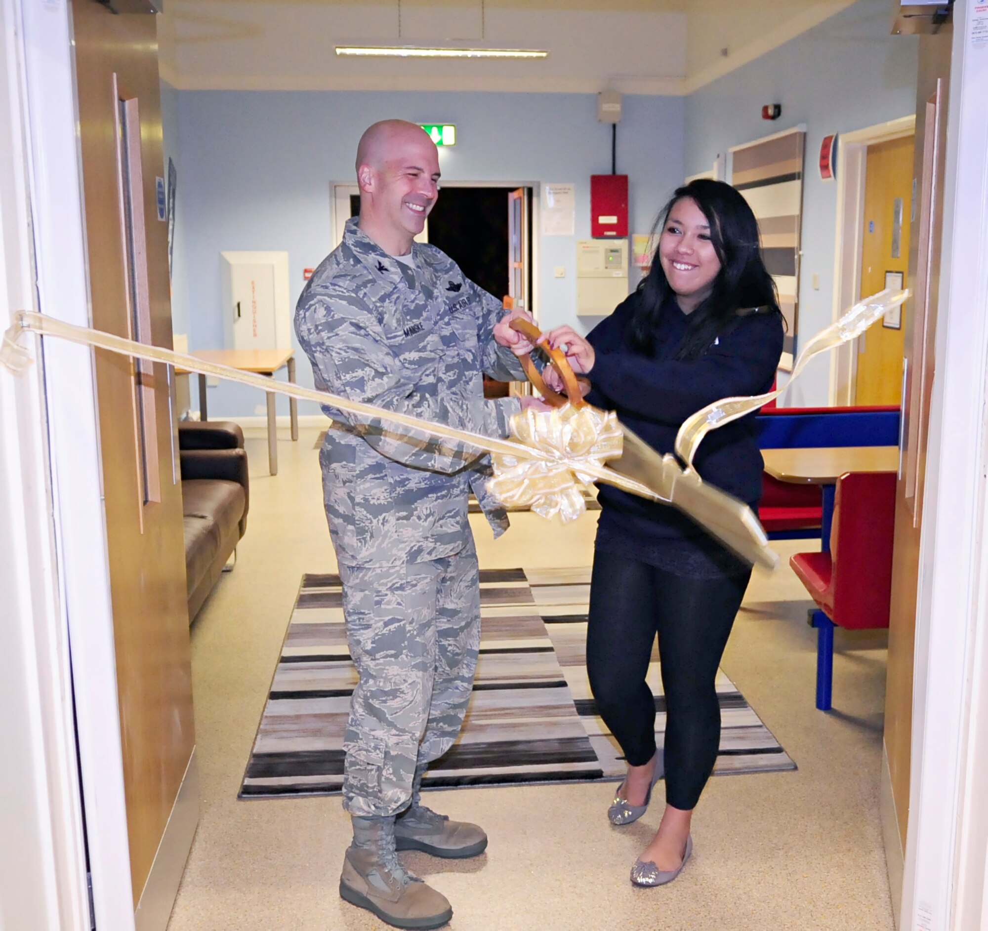 RAF MILDENHALL, England -- Col. Chad Manske, 100th Air Refueling Wing commander, teams up with Georgia Lau, RAF Mildenhall's "Youth of the year", to cut the ribbon at the base Teen Center's grand opening Nov. 17, 2010.  The ribbon cutting was held to symbolize the new beginning and life of the teen center here at RAF Mildenhall. (U.S. Air Force photo/Senior Airman Ethan Morgan)