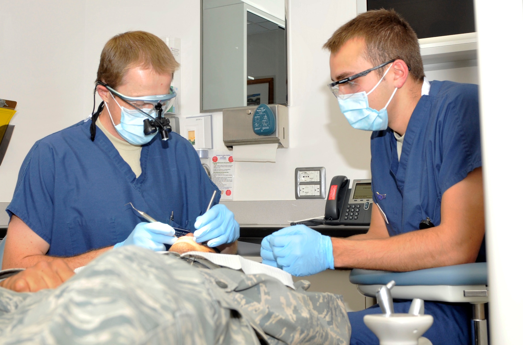 (Left) Capt. Michael Bingham and Airman 1st Class Dale Brown, 65th Medical Operations Squadron, work on a patient at the Lajes Dental Clinic.  Captain Bingham is a dentist while Airman Brown is a dental technician at the clinic. (Photo by Staff Sgt. Olufemi Owolabi)