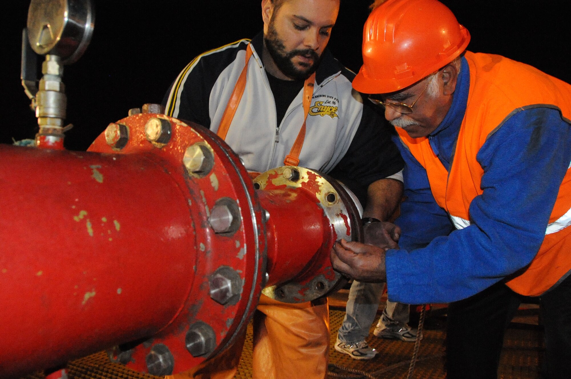 Rui Moniz (left) and Jaime Teofico, local contractors, connect a fuel hose to the oil vessel about to deliver unleaded fuel, Nov. 17, 2010.  The 65th Logistics Readiness Squadron’s Fuels Management Flight received more than 200,000 gallons of fuel to restock the base reservoir.  (U.S. Air Force photo by Tech. Sgt. Chyrece Campbell)
