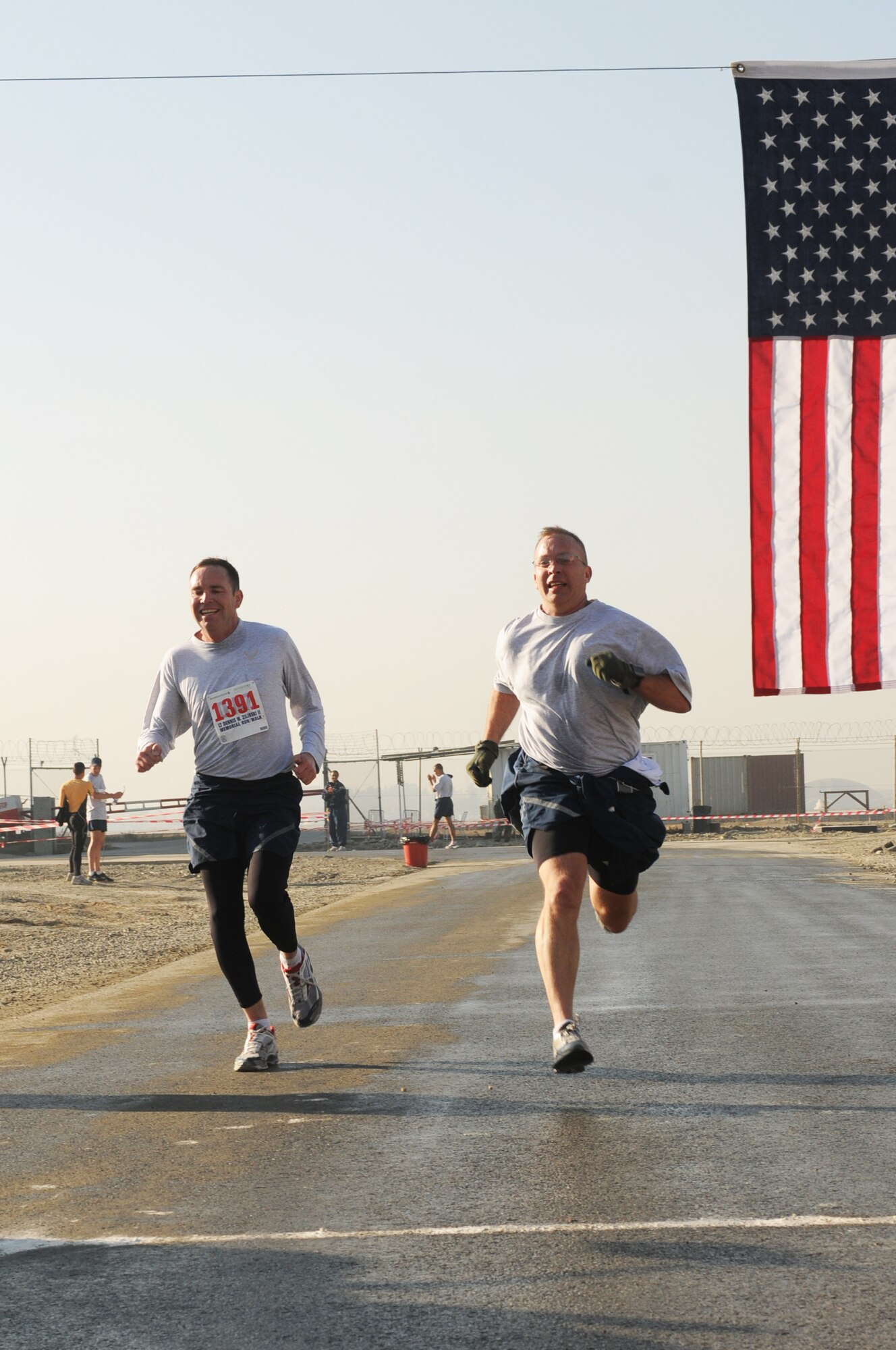 KABUL, Afghanistan -- Two runners cross the finish line at the 5th Annual LT Dennis W. Zilinski II Memorial 5K Run/Walk in "battle rattle" at Kabul International Airport. Nov. 19. The race is held in honor os 1st Lt. Dennis Zilinski who died supporting combat operations in Iraq in 2005. (US Navy photo by MC3 Jared Walker)