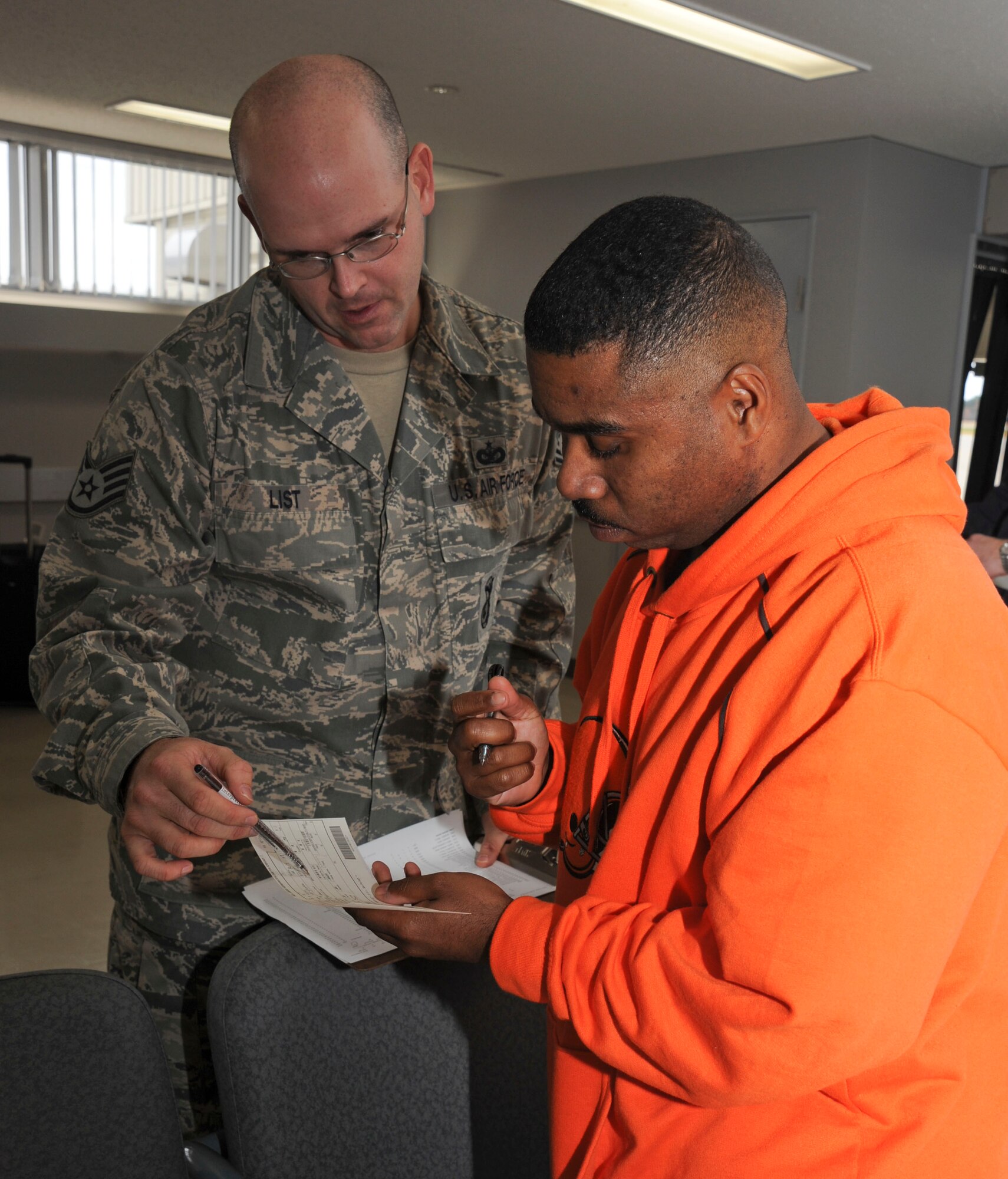 U.S. Air Force Staff Sgt. Ross List, 35th Security Forces Squadron NCO in charge of customs and confinement, demonstrates how to complete to an embarkation card  to Tech. Sgt. Marco McDowell 35th Maintenance Squadron, at Misawa Air Base, Japan, Nov. 15, 2010. Once they arrive, travelers fill out Government of Japan Disembarkation cards. (U.S. Air Force photo by Tech. Sgt. Russell McBride/Released)