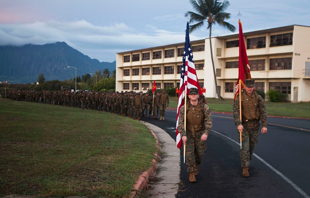 Sgt. Matthew Bonnette, finance clerk, and Cpl. Vitaly Zefirov, an administrative clerk with Headquarters Battalion, carry the battalion colors in front of a formation of approximately 400 Marines and sailors on a 4.2-mile holiday food drive hike on Marine Corps Base Hawaii, Nov. 19, 2010. Lacing up their boots and donning packs weighed down by nonperishable foods, the Marines and sailors opened their cabinets to donate to the Armed Services YMCA’s Operation Harvest. After carrying 3,580 pounds of food on the hike, they stopped at the base chapel to fill boxes with the goods.
