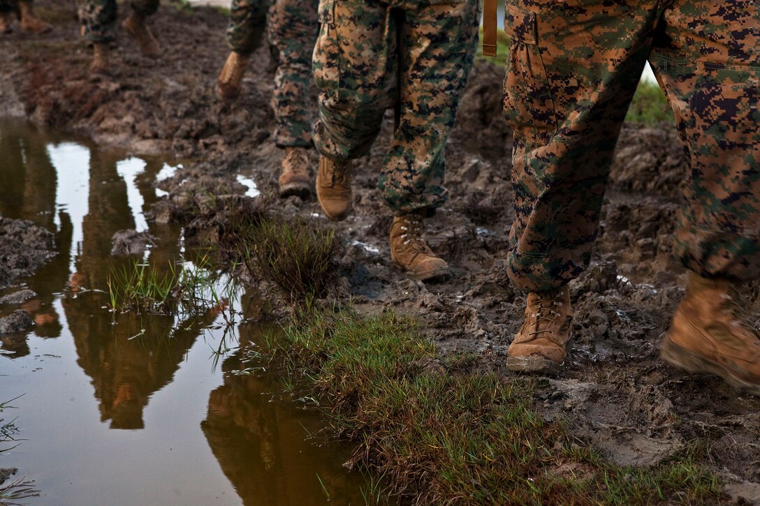 Marines and sailors with Headquarters Battalion trek through a muddy tank trail during a 4.2-mile holiday food drive hike on Marine Corps Base Hawaii, Nov. 19, 2010. Lacing up their boots and donning packs weighed down by nonperishable foods, they opened their cabinets to donate to the Armed Services YMCA’s Operation Harvest. After carrying 3,580 pounds of food on the hike, the Marines and sailors stopped at the base chapel to fill boxes with the goods.