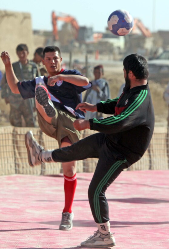 Cpl. Ernesto Garibay, an electrical engineer attached to 2nd Battalion, 9th Marine Regiment, kicks the ball the same time an ANA soldier does during an Eid celebratory soccer tournament at Marine Corps Forward Operations Base Camp Hansen, Nov. 20. Marines, Afghanistan National Army soldiers, Interpreters and local nationals all competed during the event. The crowd enjoyed live music, fresh fruit and gifts, such as soccer balls and sports jerseys.