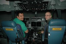 JOINT BASE LEWIS-MCCHORD, Wash.- Comedian Carlos Mencia, gets to "fly" a C-17 Globemaster III in a flight simulator with his "co-pilot", Capt. Eric Hodges, a pilot and Reservist with the 728th Airlift Squadron, Nov. 19. Experiencing the simulator was part of Mencia's "Tour for the Troops", sponsored by the Air Force Reserve. Mencia gave a stand-up performance at McChord Field that evening for almost 2,300 troops from all branches of the military. (U.S. Air Force photo/Master Sgt. Jake Chappelle) 