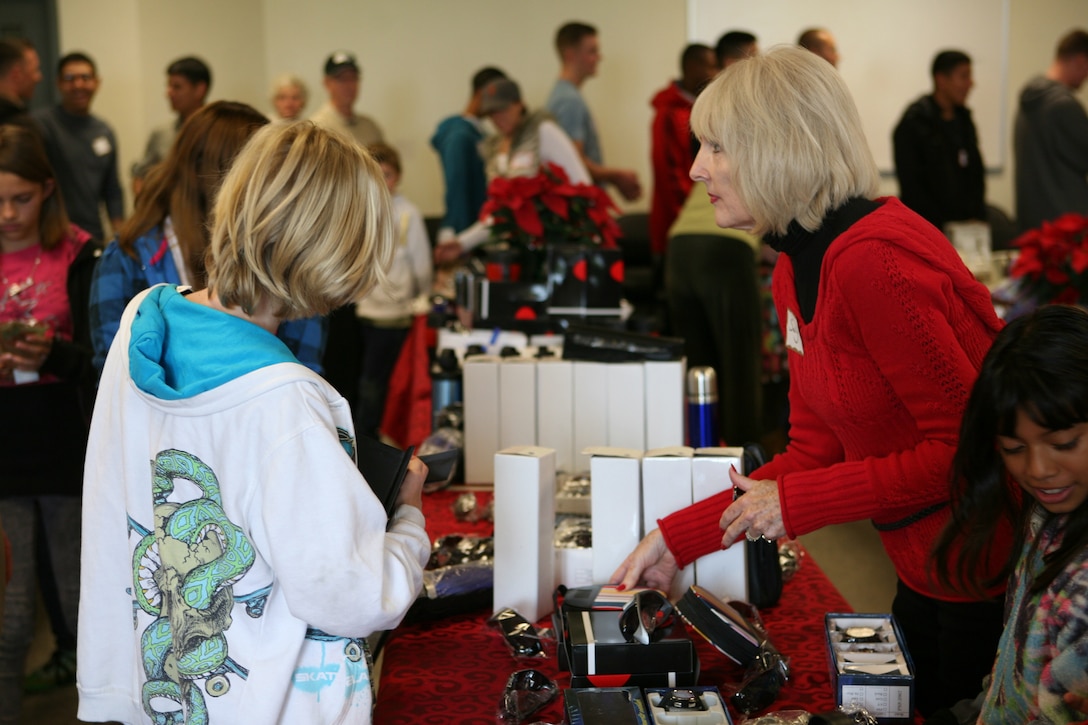 Sally L. McCoy, a Children Giving Gifts volunteer from Orange County, Calif., mans a gift table at Children Giving Gifts, a non-profit organization allowing children to select gifts for their parents, in San Mateo, Nov. 20. The gifts distributed met the requirements of the Marine Corps gift policy, and were purchased wholesale from monetary donations to the organization.