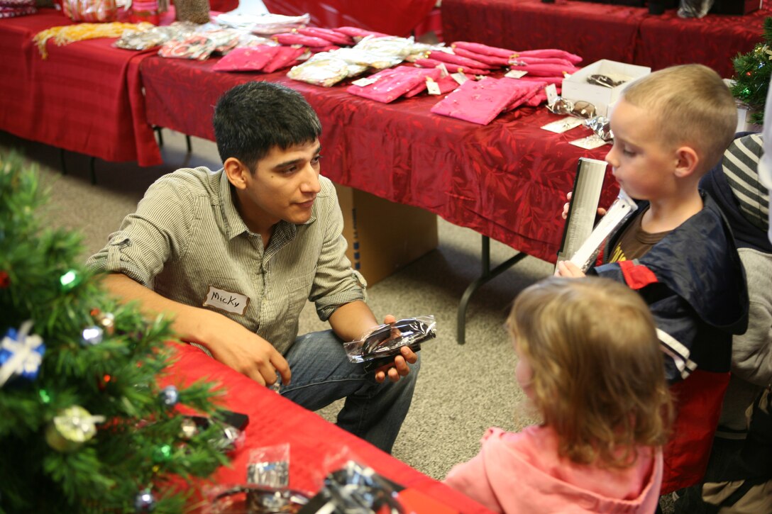 Petty Officer 3rd Class Micky A. Montoya, a corpsman with Headquarters and Service Company, 2nd Battalion, 5th Marine Regiment, talks to Sophia and Nathan Gaff about the gifts they selected for their parents at Children Giving Gifts in San Mateo, Nov. 20.  Nathan and Sophia are the children of Staff Sgt. Michael Gaff, and were two of more than a thousand kids participating in the first Children Giving Gifts hosted at Camp Pendleton.