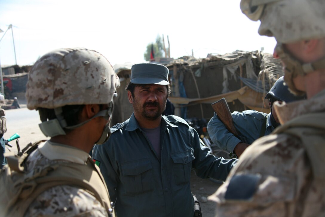 Corporal Michael Creighton, a team leader with the Police Mentoring Team, 3rd Battalion, 5th Marine Regiment, talks to the local Afghan Uniformed Police commander at a nearby checkpoint, Nov. 21. The commander explained to Creighton that the police stationed received incoming fire earlier that morning and how his policemen responded.