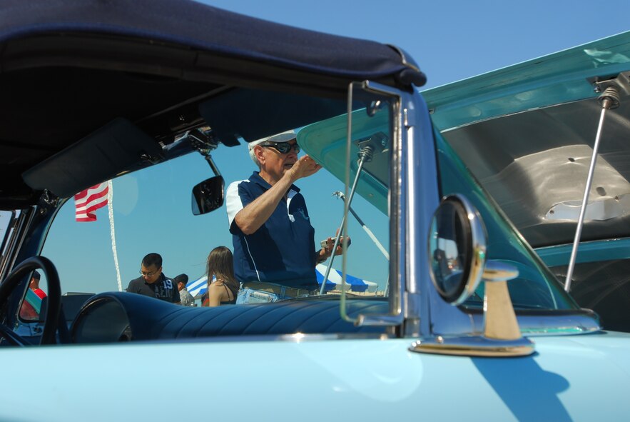 Norman Brinkmeyer shows off his 1957 Ford Thunderbird, which features a carburetor he redesigned and rebuilt, during the car show of the 433rd Airlift Wing Family Day. (U.S. Air Force photo/Airman 1st Class Brian McGloin)