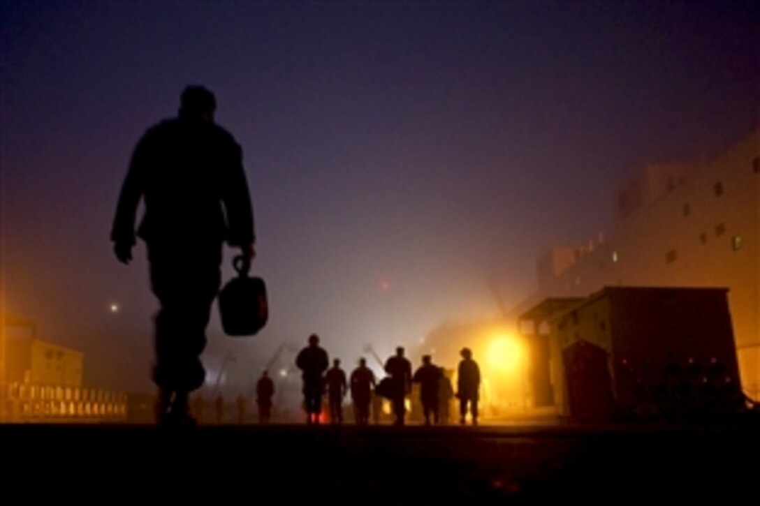 U.S. Navy sailors walk through early morning fog to the messing and berthing barge of the amphibious assault ship USS Bonhomme Richard in San Diego, Nov. 18, 2010. The Bonhomme Richard is preparing for a dry-dock maintenance period in December.