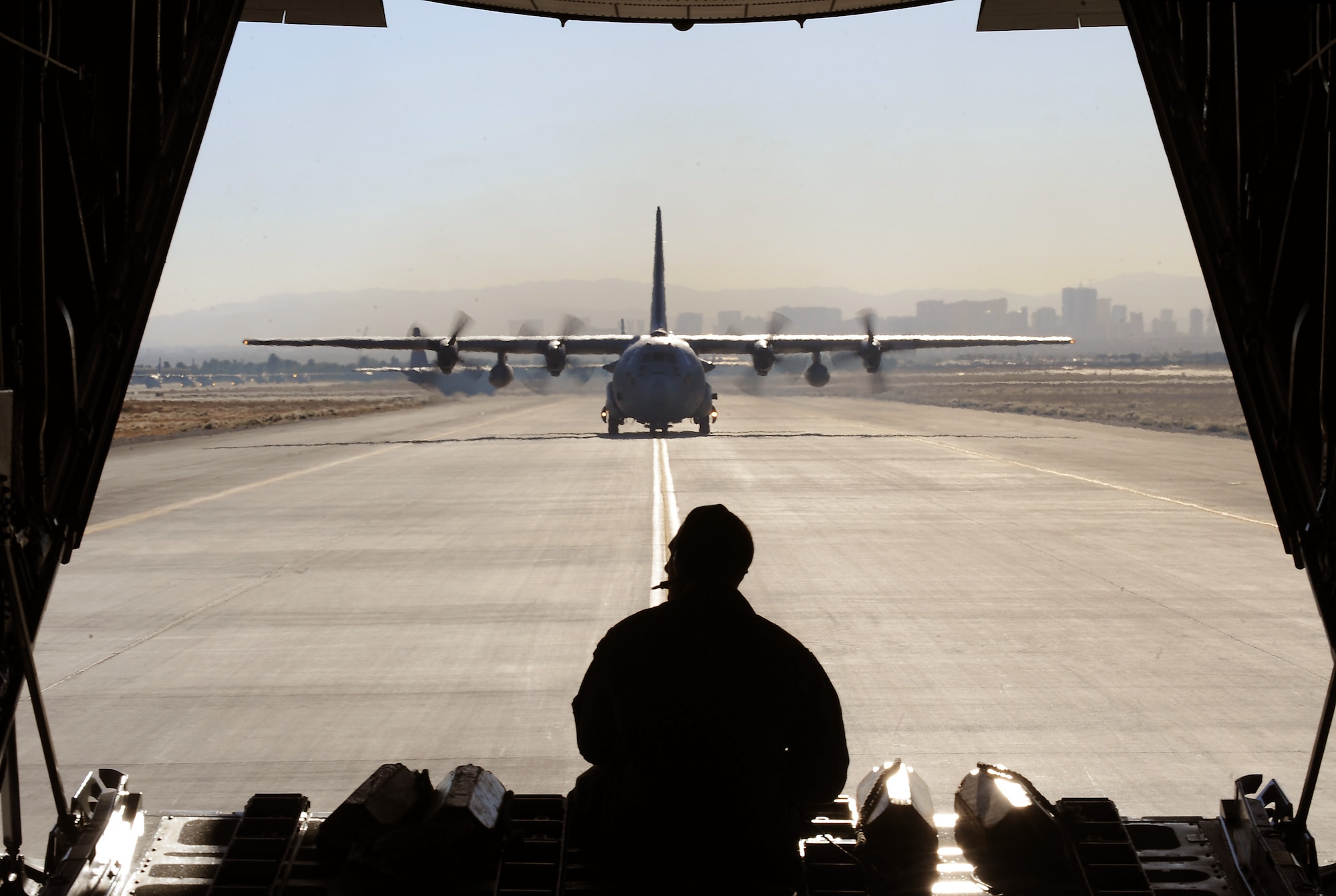 NELLIS AIR FORCE BASE, Nev.-- Staff Sgt. Grant Lane, 29th Weapons Squadron, Little Rock Air Force Base, Ark., watches a C-130 Hercules taxi Nov 17 at Nellis during a Mobility Air Forces Exercise. More than 40 U.S. Air Force C-17 Globemaster III and C-130 Hercules cargo aircraft assembled in aerial formations over the Nevada Test and Training Range to conduct air and ground operations as part of the bi-annual U.S. Air Force Weapons School MAFEX. (U.S. Air Force photo/ Master Sgt. Kevin J. Gruenwald)