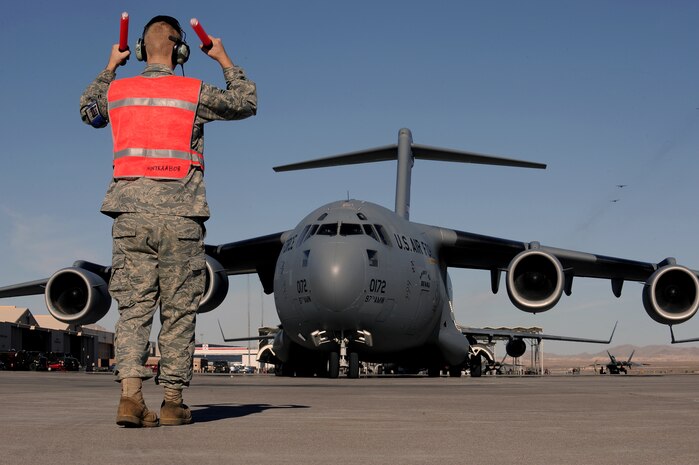 NELLIS AIR FORCE BASE, Nev. -- Airman 1st Class David Berger, crew chief with the 446th Aircraft Maintenance Squadron, McChord Air Force Base, marshalls in a C-17 Globemaster III at Nellis Air Force Base from participating in the Mobility Air Forces Exercise over the Nevada Test and Training Range, Nov 17. Approximately 40 C-17 Globemaster and C-130 Hercules cargo aircraft will assemble in aerial formations over the NTTR to conduct air and ground operations as part of the bi-annual, U.S. Air Force Weapons School Mobility Air Forces Exercise. (U.S. Air Force Photo by Senior Airman Brett Clashman)(Released)