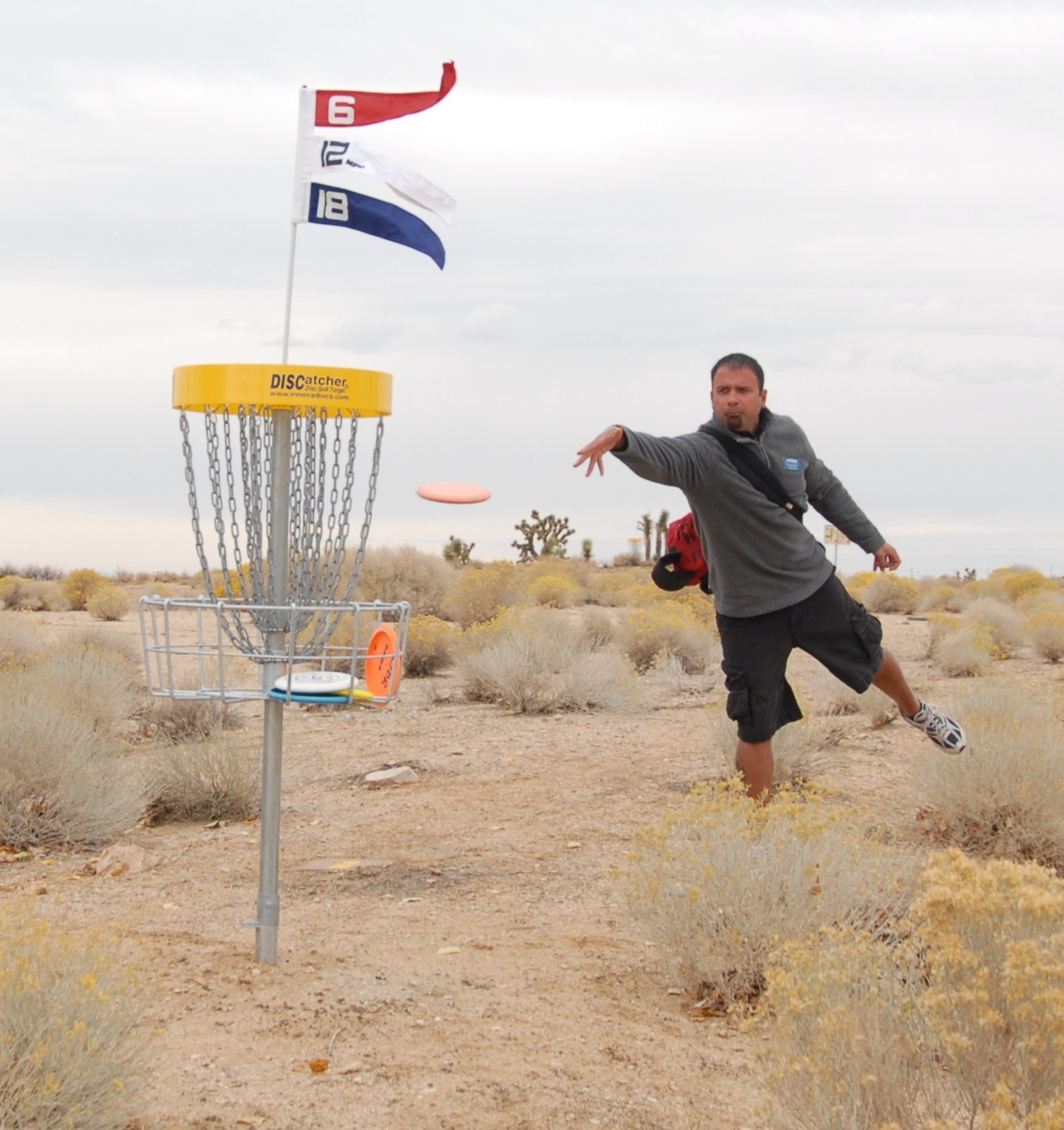 Fernando Brown, Outdoor Recreation assistant director, “putts” in a disc at Edwards’ new disc golf course.  Instead of a small hole, disc golf uses a basket to catch the discs. The Mojave Greens Disc Golf Course officially opened up with a ribbon-cutting ceremony, Nov. 19.  (Air Force photo by Kenji Thuloweit)