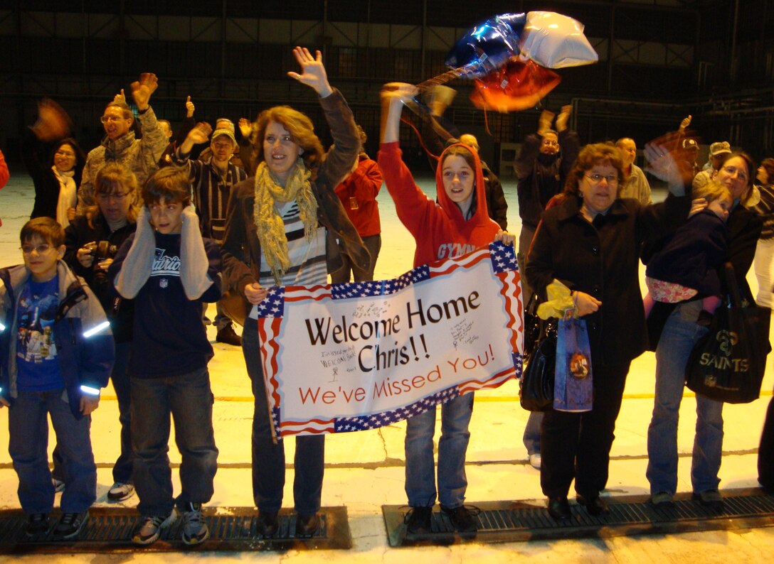 Family members of the musical ensemble New Harmony hold signs and cheer in anticipation of the arrival of their loved ones from a 120-day deployment Nov. 20, 2010, at Wright-Patterson Air Force Base, Ohio. The 10-member group, made up of Band of Flight members, performed in Costa Rica, Guatemala, Panama as part of the U.S. Navy's Continuing Promise 2010 mission. (U.S. Air Force photo/Ron Fry) 