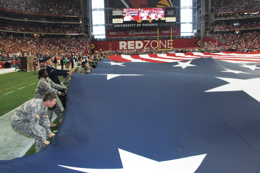 Airmen and other servicemembers unfurl teh U.S. flag on November 14th during the Arizona Cardinals game in Glendale, Arizona.  In addition to the flag support detail, other Airmen had the opportunity to attend the game for free thanks to the Bidwell family from the Arizonal Cardinals who donated more than 400 tickets to Luke Air Force Base.  (U.S. Air Force photo/Staff Sgt. Steve Nabor)
