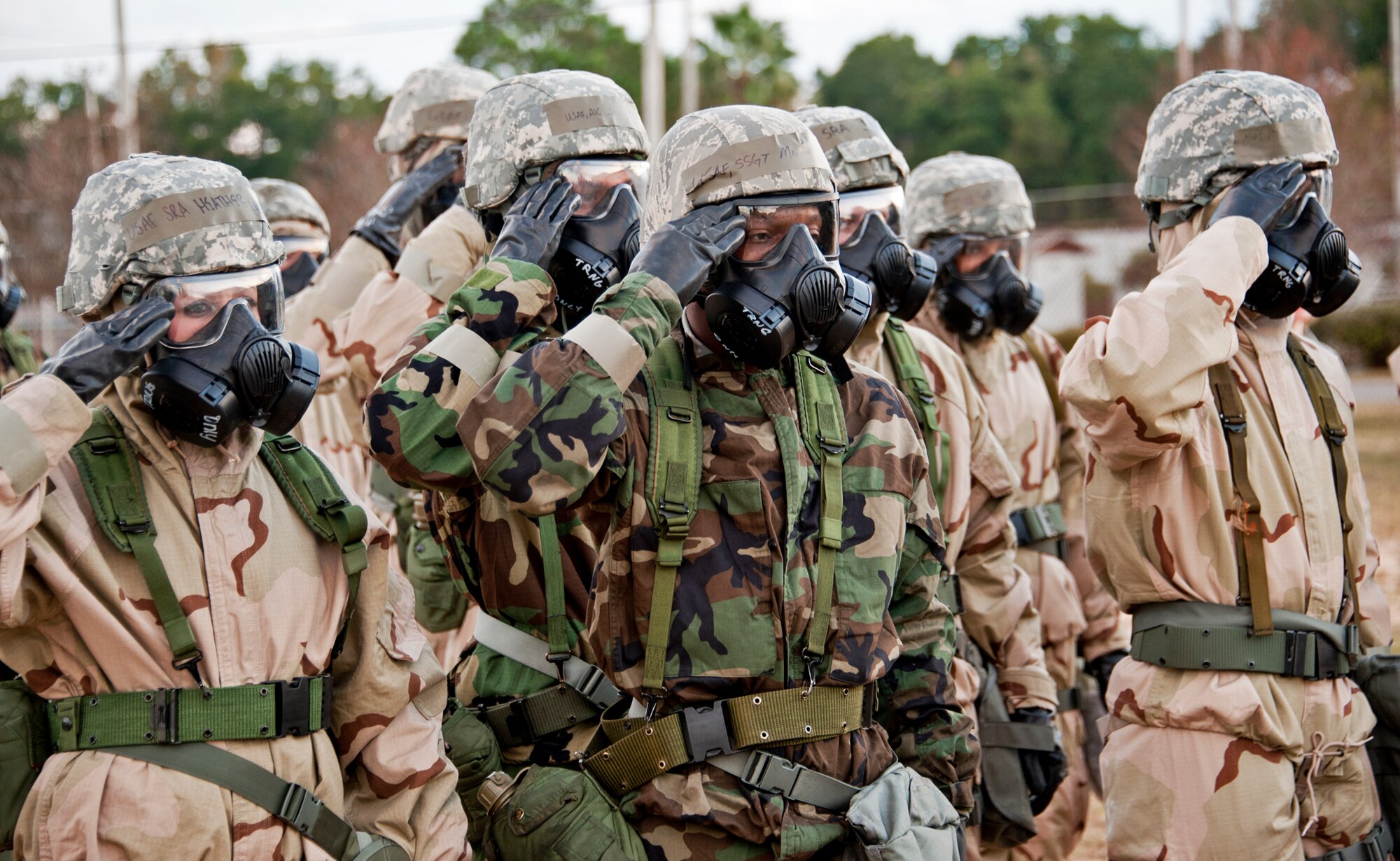 Senior Airman Heather Holland, 96th Force Support Squadron, and Staff Sgt. Michael Fleming, 96th Communications Squadron, salute during the National Anthem at Eglin Air Force Base, Fla., Nov. 18.  Approximately 50 Air Base Wing Airmen faced the flag and saluted in full Mission Oriented Protective Posture gear while attending chemical, biological, radiological, nuclear, and explosive training.  Large groups of Eglin personnel attended the training as part of Phase II exercise, Nov. 17 and 18.  (U.S. Air Force photo/ Samuel King Jr.)