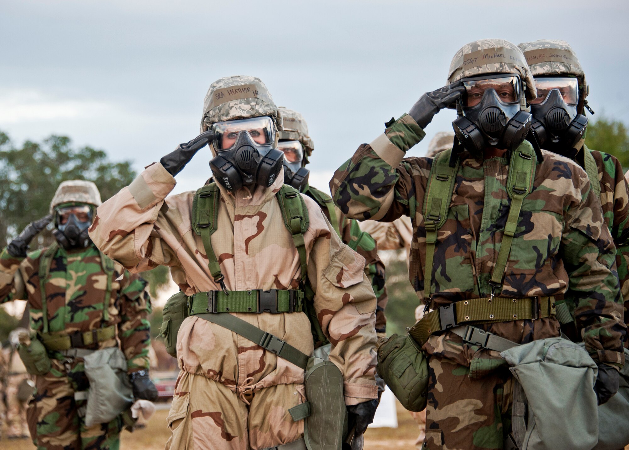 Senior Airman Heather Holland, 96th Force Support Squadron, and Staff Sgt. Michael Fleming, 96th Communications Squadron, salute during the National Anthem at Eglin Air Force Base, Fla., Nov. 18.  Approximately 50 Air Base Wing Airmen faced the flag and saluted in full Mission Oriented Protective Posture gear while attending chemical, biological, radiological, nuclear, and explosive training.  Large groups of Eglin personnel attended the training as part of Phase II exercise, Nov. 17 and 18.  (U.S. Air Force photo/ Samuel King Jr.)
