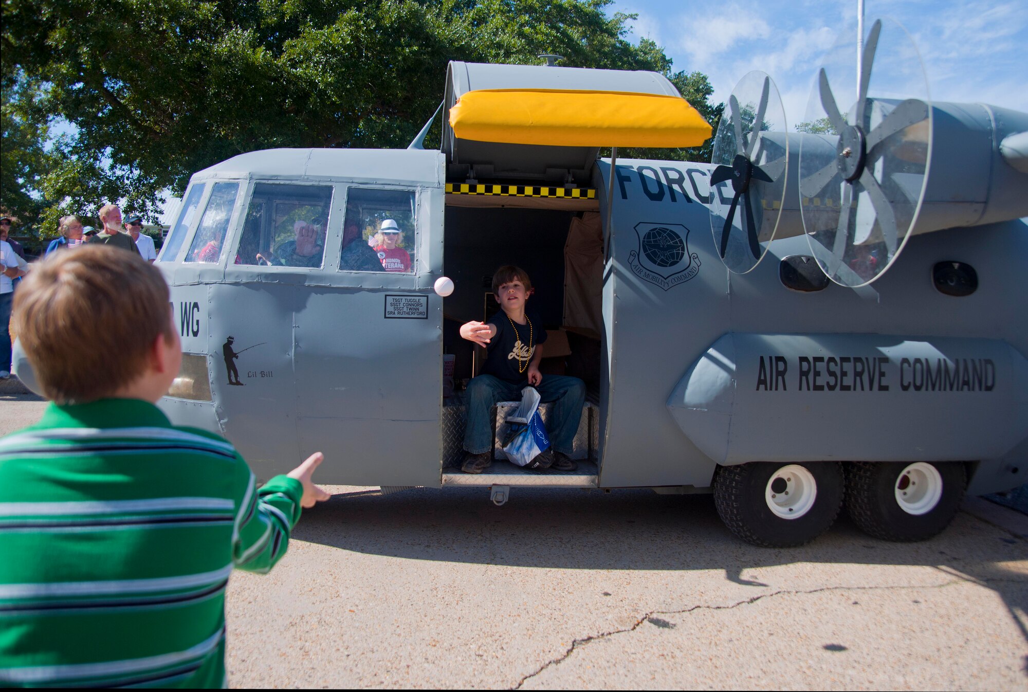 Peter Wypyszinski, son of Tech. Sgt. Peter Wypyszinski, Air Force Reserve Command recruiter, throws toys from the 403rd Wing's mini C-130J, "Lil' Bill," to onlookers at the annual Gulf Coast Veterans Day parade held Nov. 13 in Biloxi, Miss.